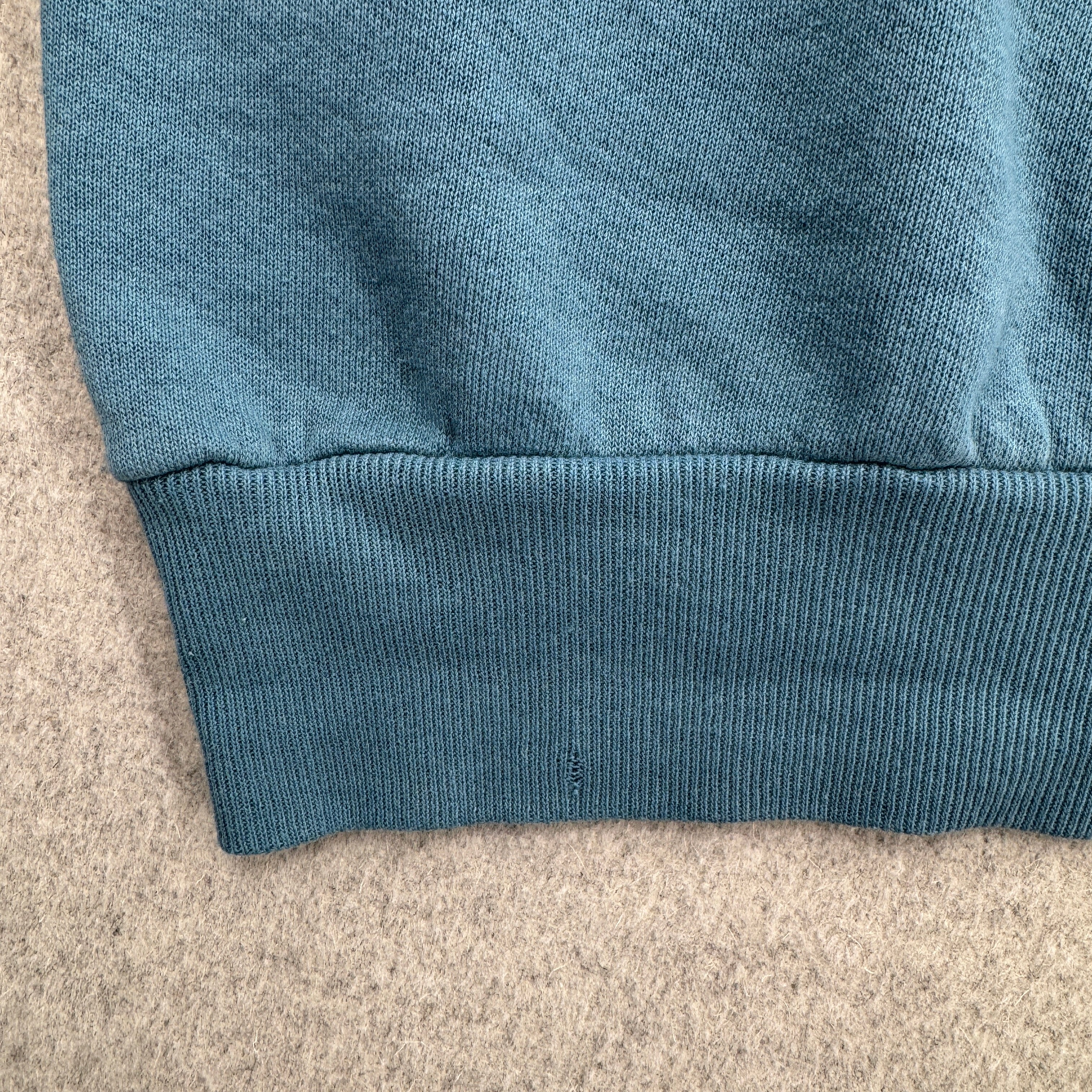 Close-up of a blue fabric edge on a beige surface. bottom hem has small hole