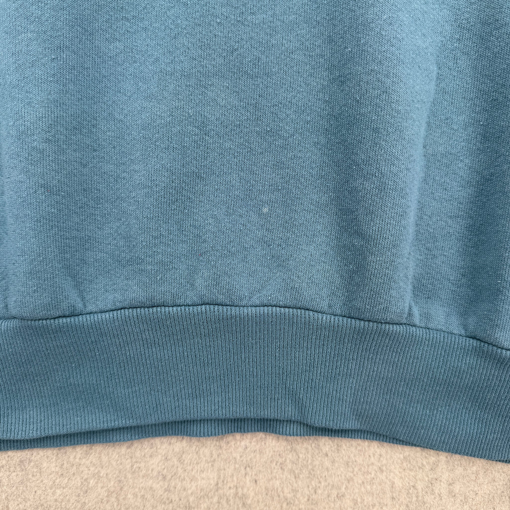 Close-up of a blue fabric texture on a beige surface. bottom of sweatshirt has some light faint stain spots