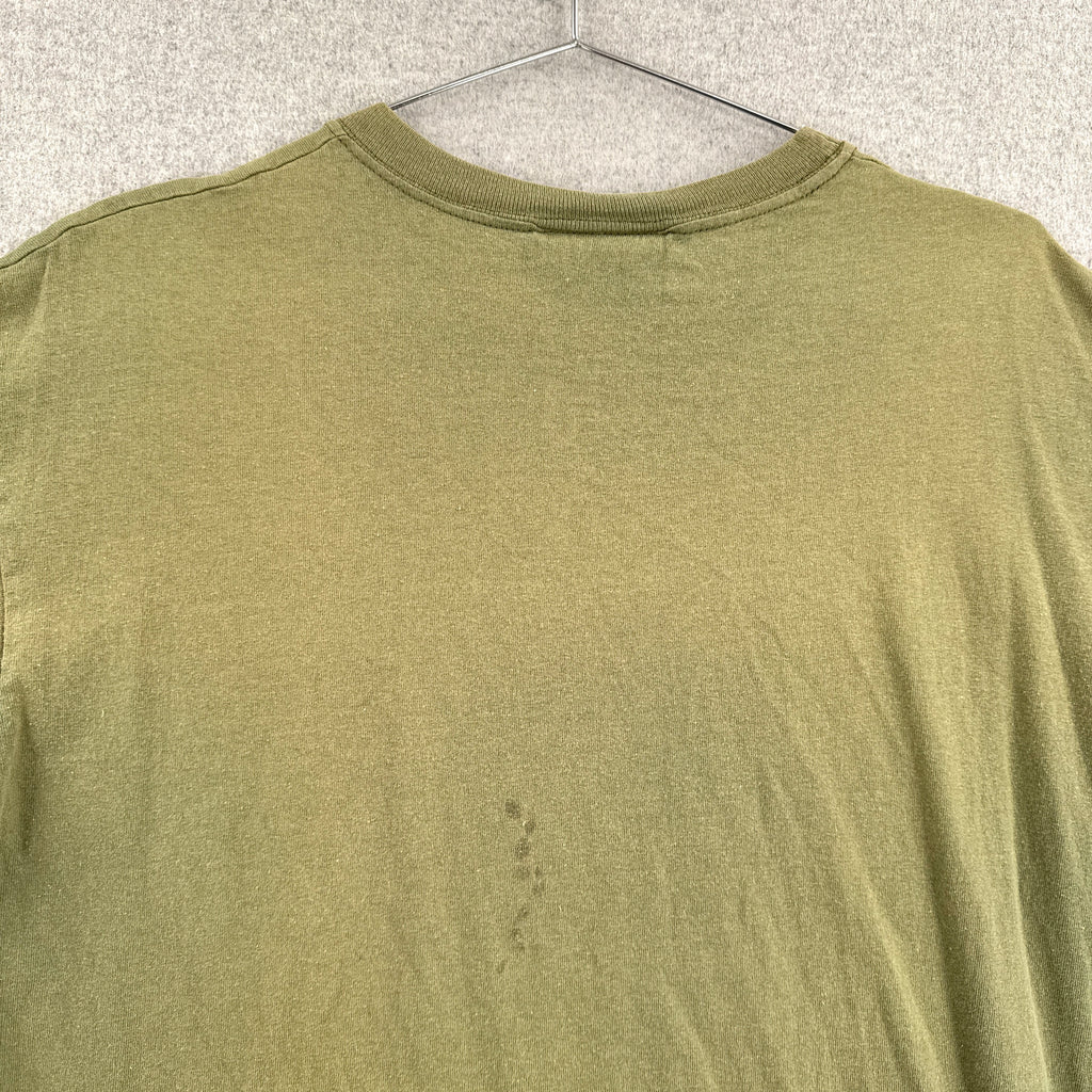 Green t-shirt on a hanger with a visible stain on the back