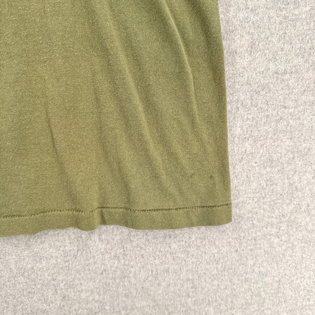 Close-up of a green fabric edge on a textured gray background. small stain spot near edge