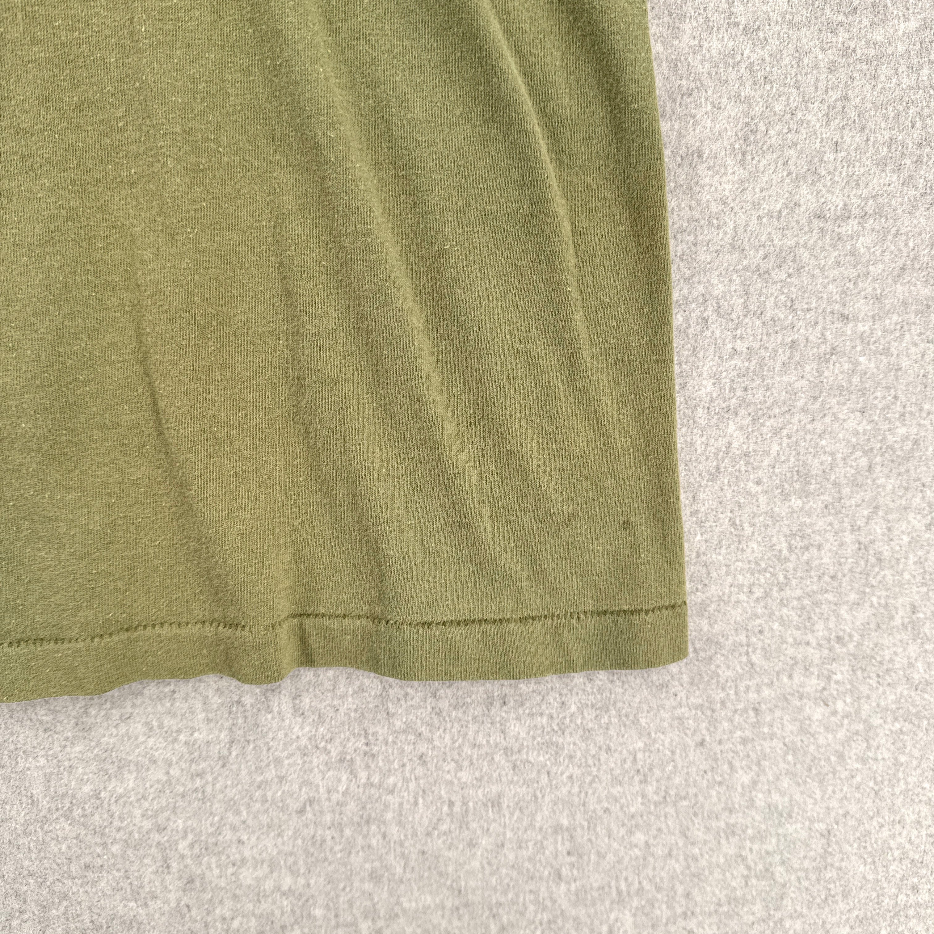 Close-up of a green fabric edge on a textured gray background. small stain spot near edge