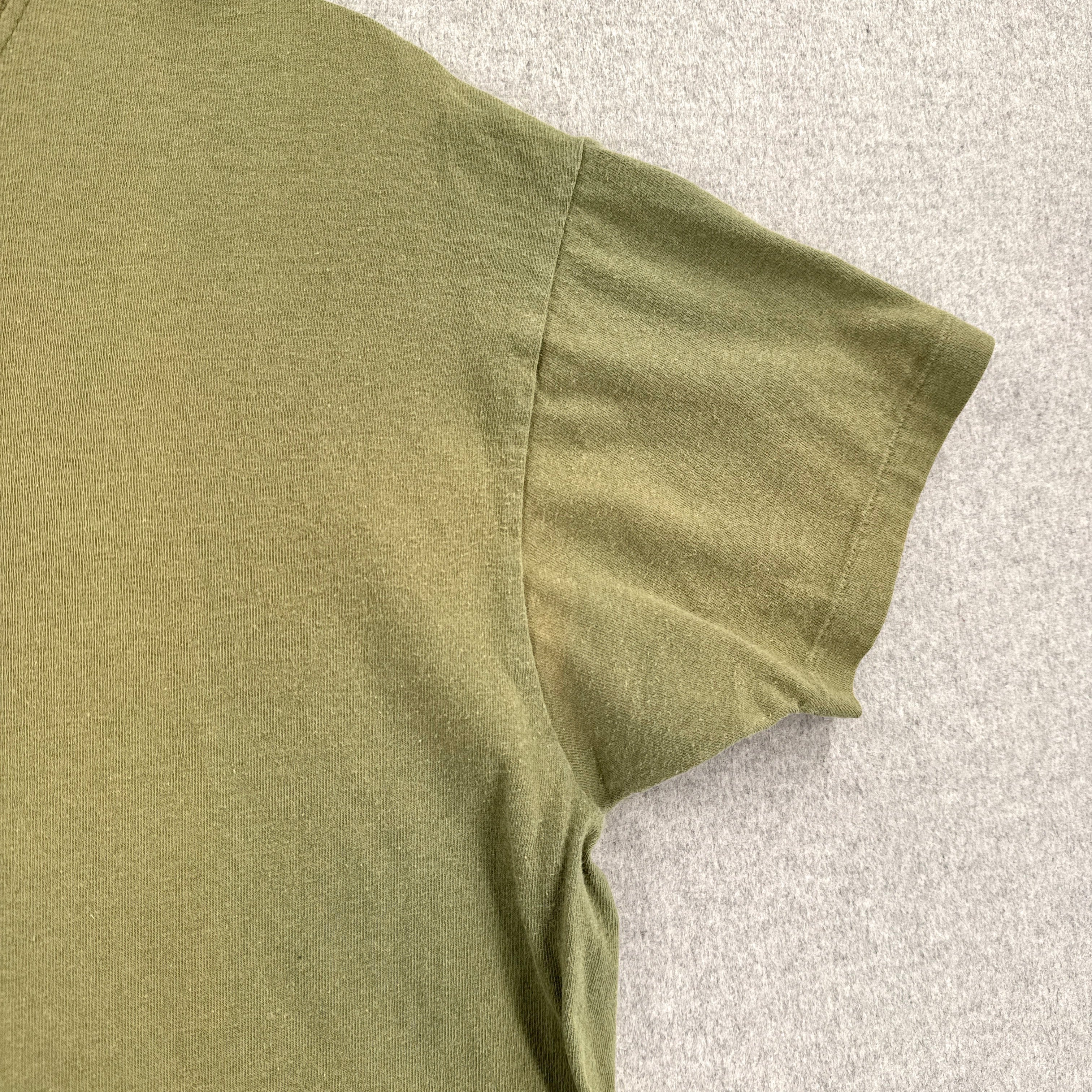 Green sleeveless shirt on a light gray textured background