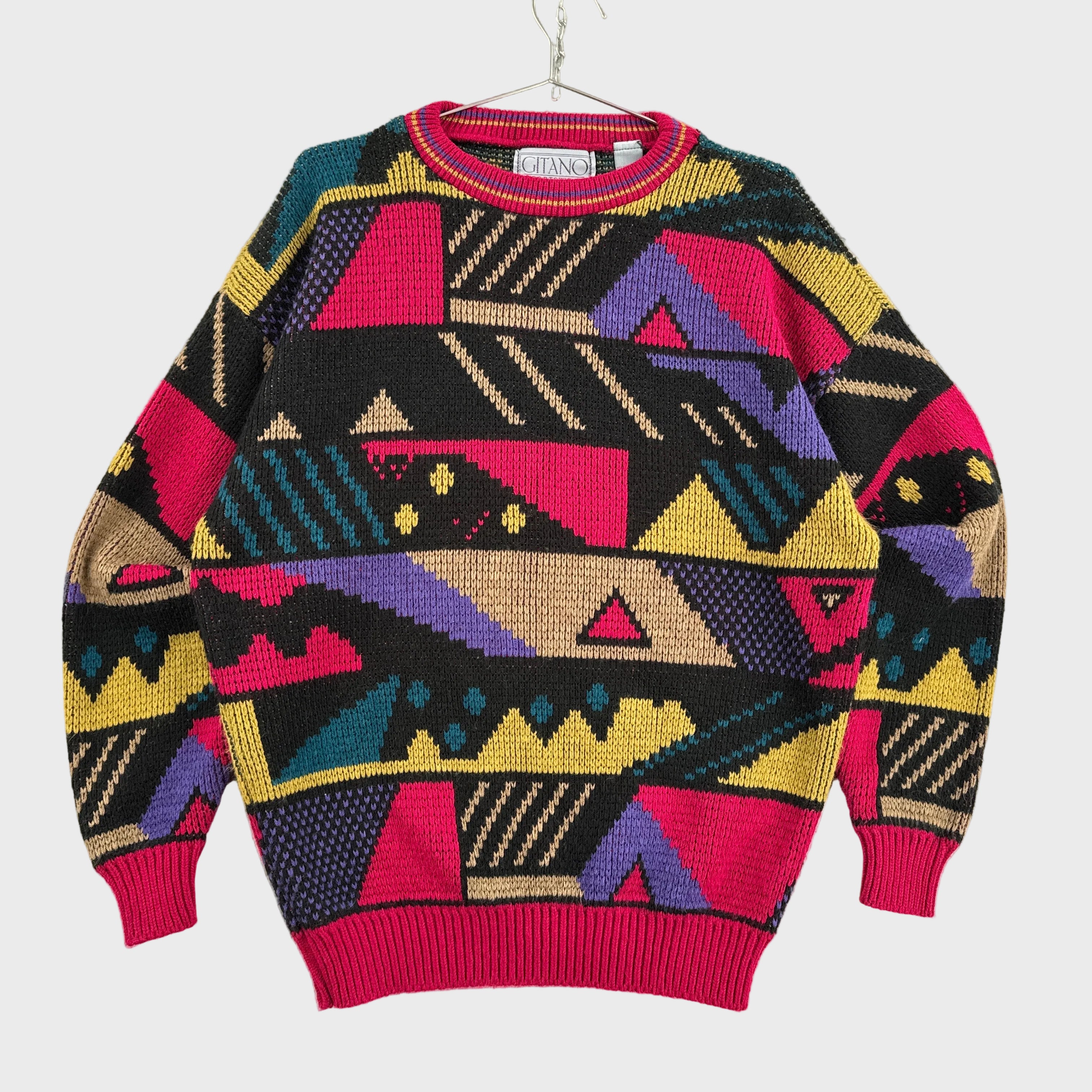 Colorful geometric patterned sweater on a beige surface. Red, pink, purple, yellow