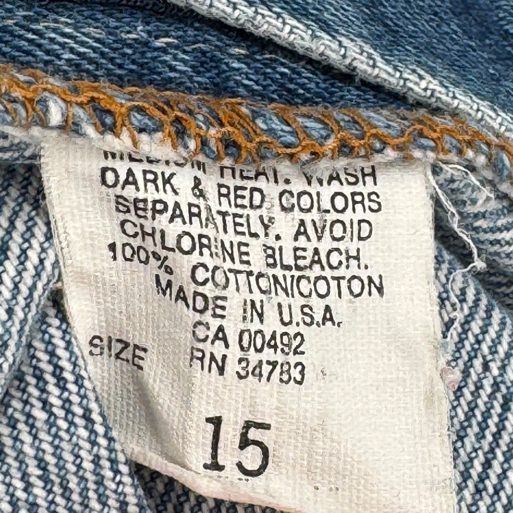 Label on denim fabric with washing instructions and product details. Made in USA size 15