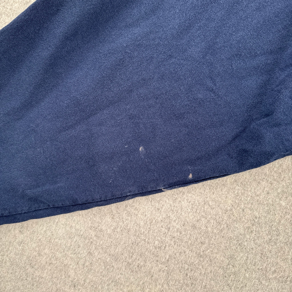 Close-up of a blue fabric edge on a beige carpet. small white stain spots on sleeve
