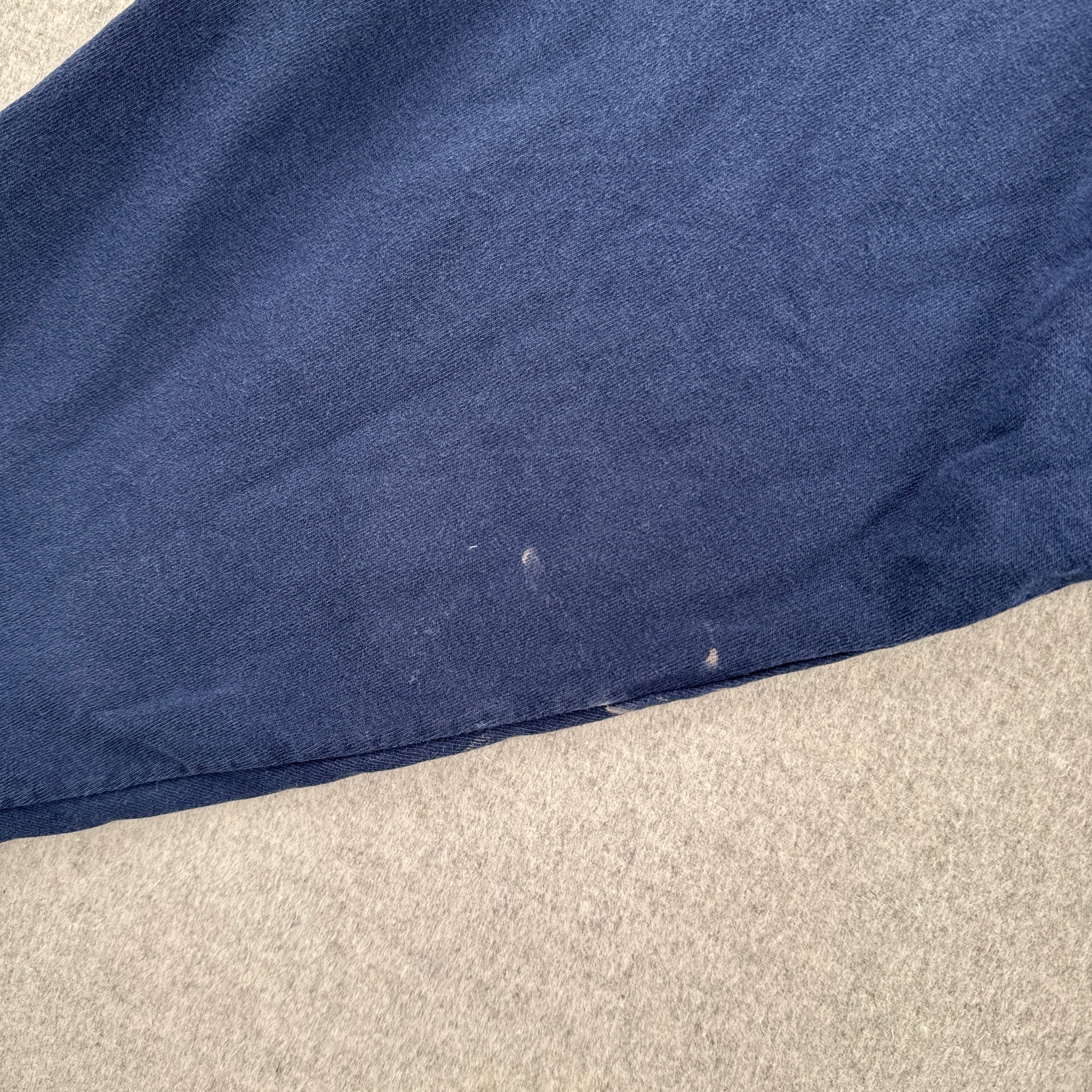 Close-up of a blue fabric edge on a beige carpet. small white stain spots on sleeve