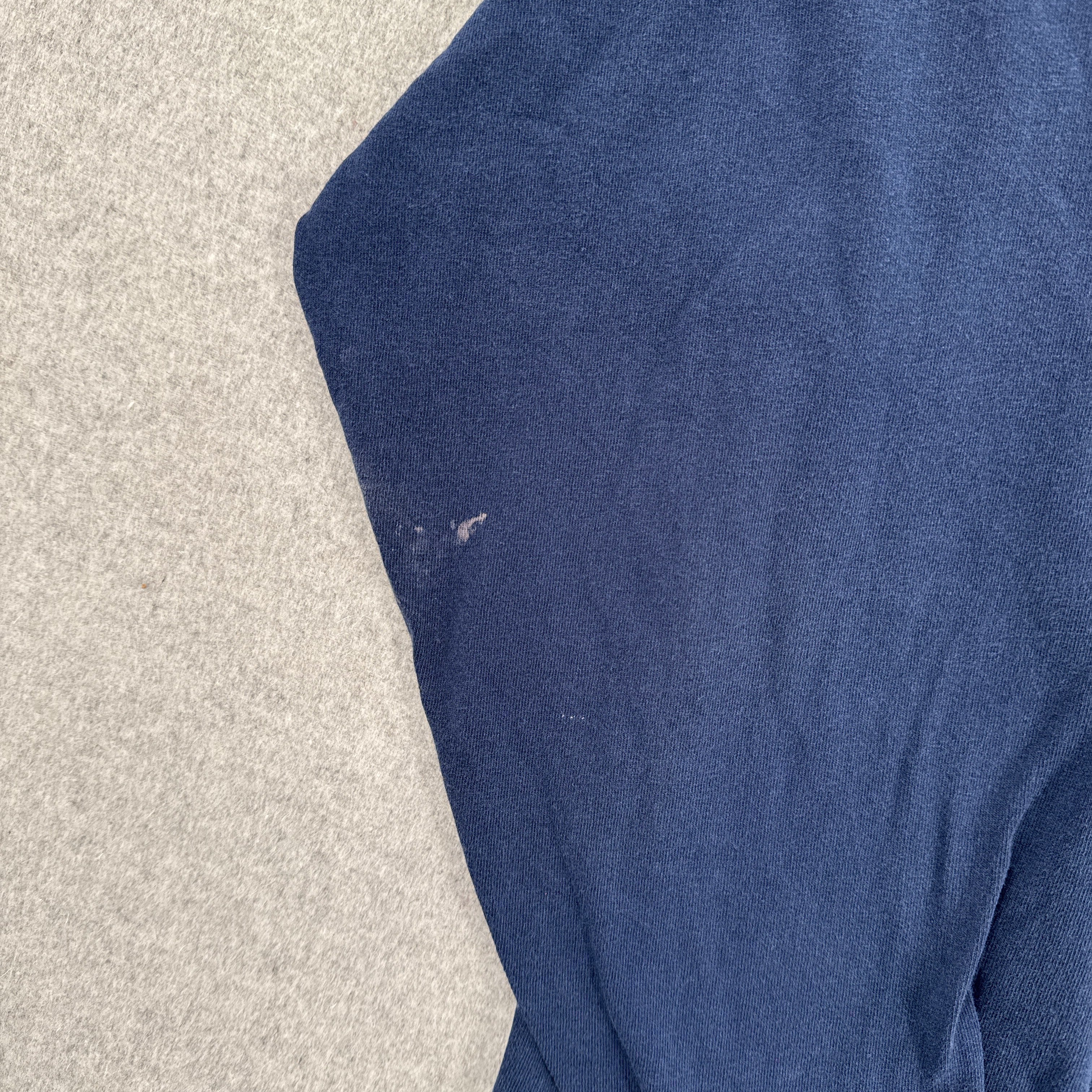 Blue fabric on a textured beige surface. stain spots on sleeve