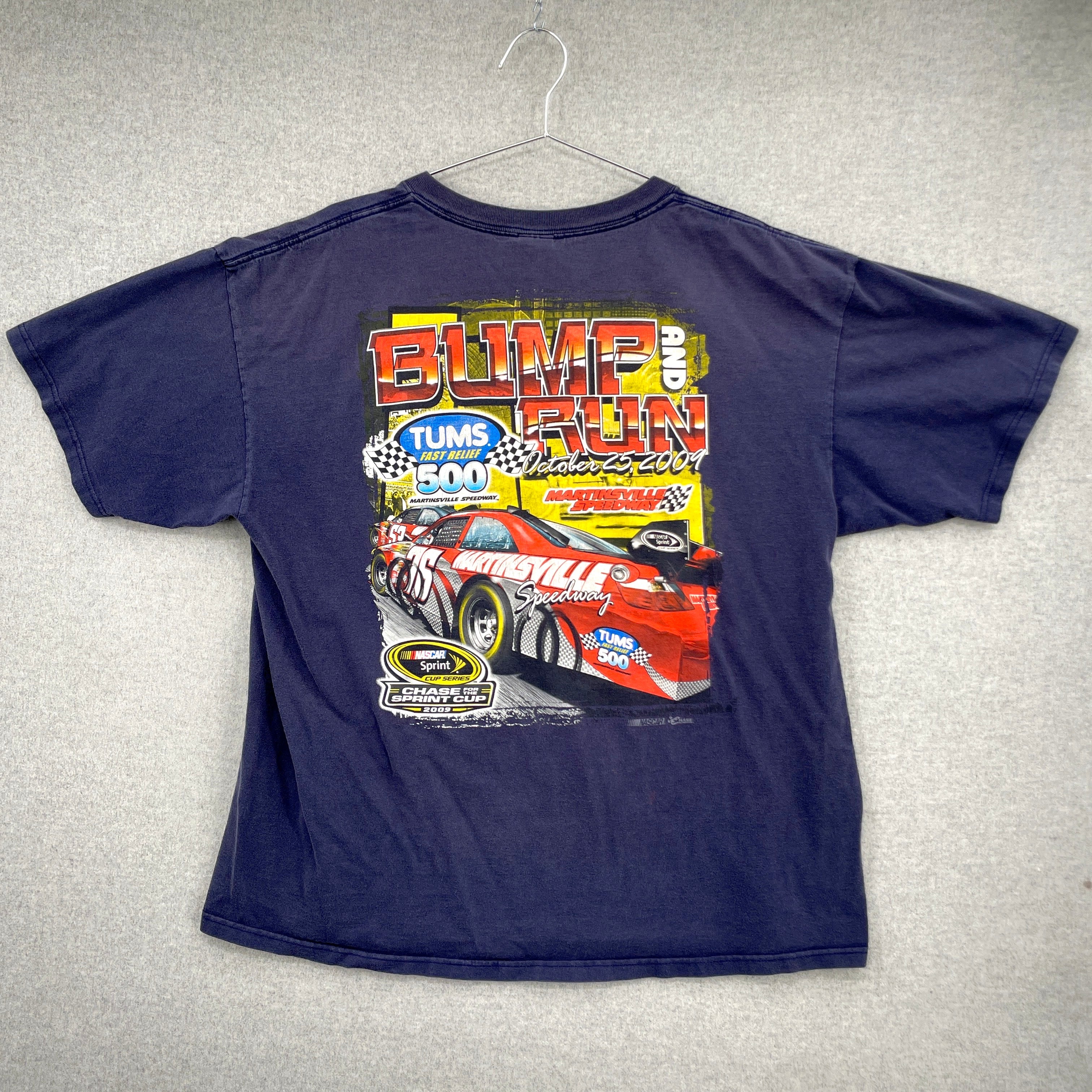 Back of the blue t-shirt with race car graphic on a gray background. Big letters "Bump and Run" with a race car for NASCAR