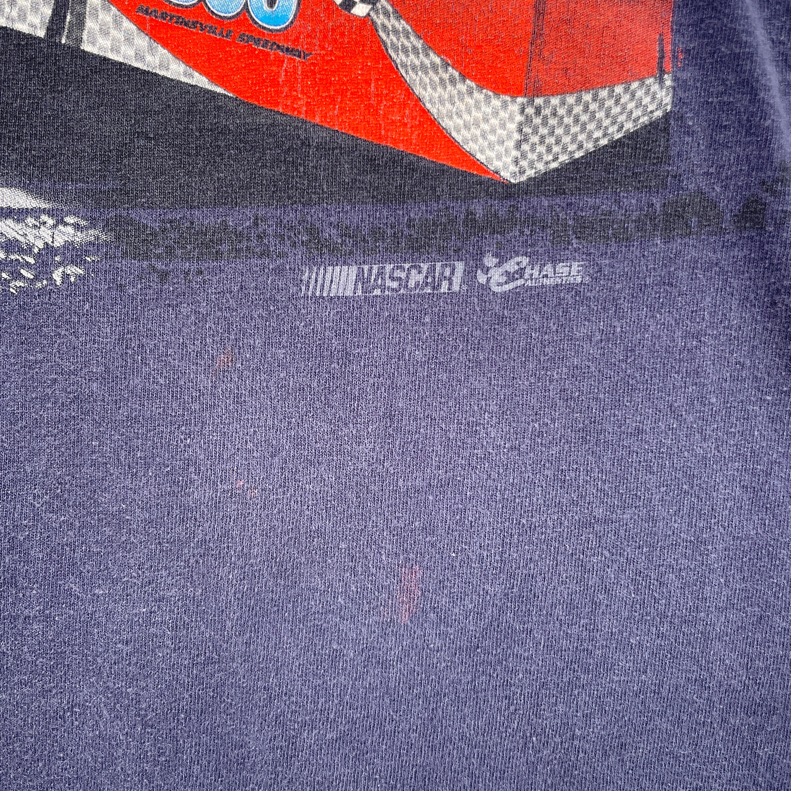 Close-up of a blue shirt with a small red stain spot under the graphic