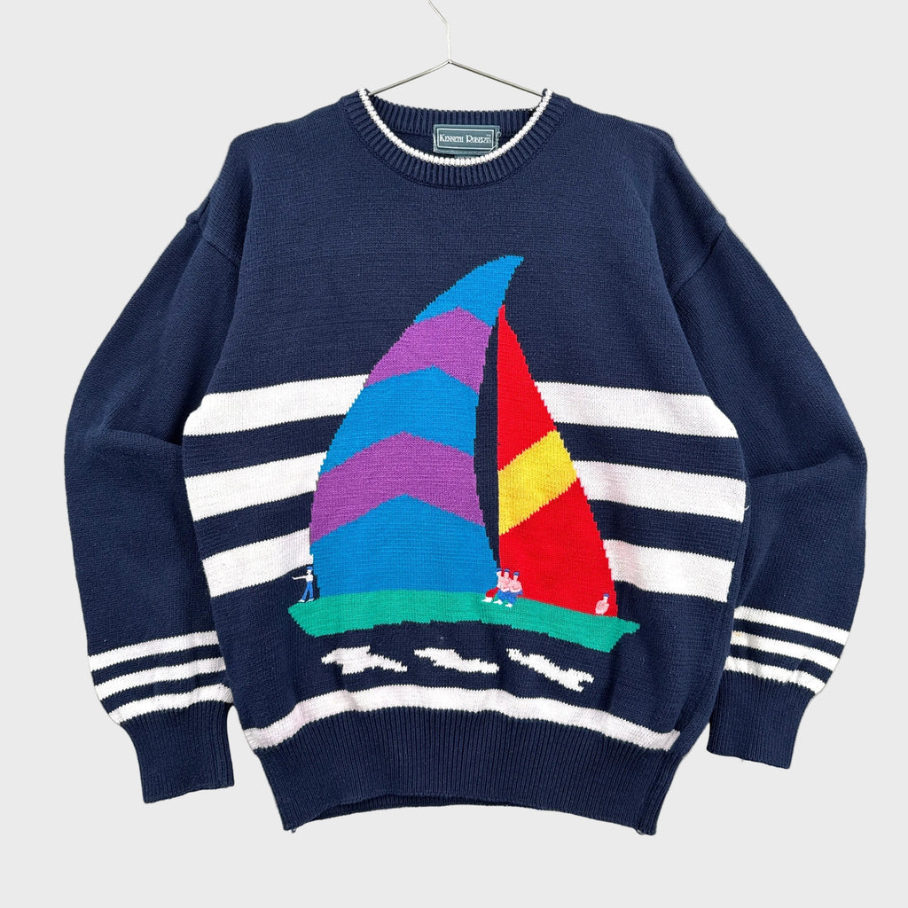 Navy sweater with colorful sailboat design on a gray background