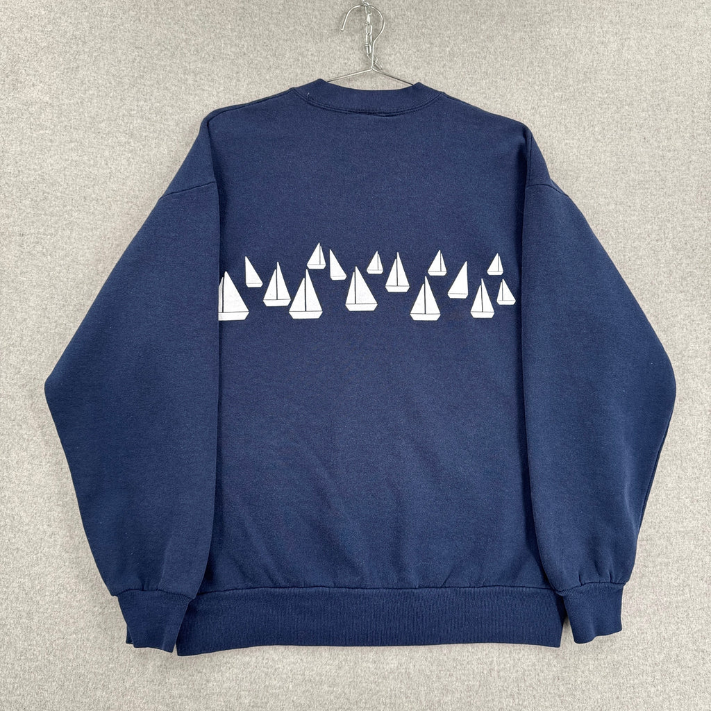 Navy blue sweatshirt with white sailboat pattern on a textured gray background