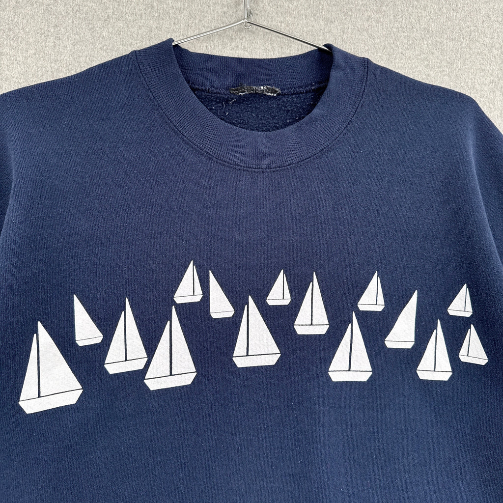 Navy blue sweatshirt with white sailboat pattern on a textured gray background