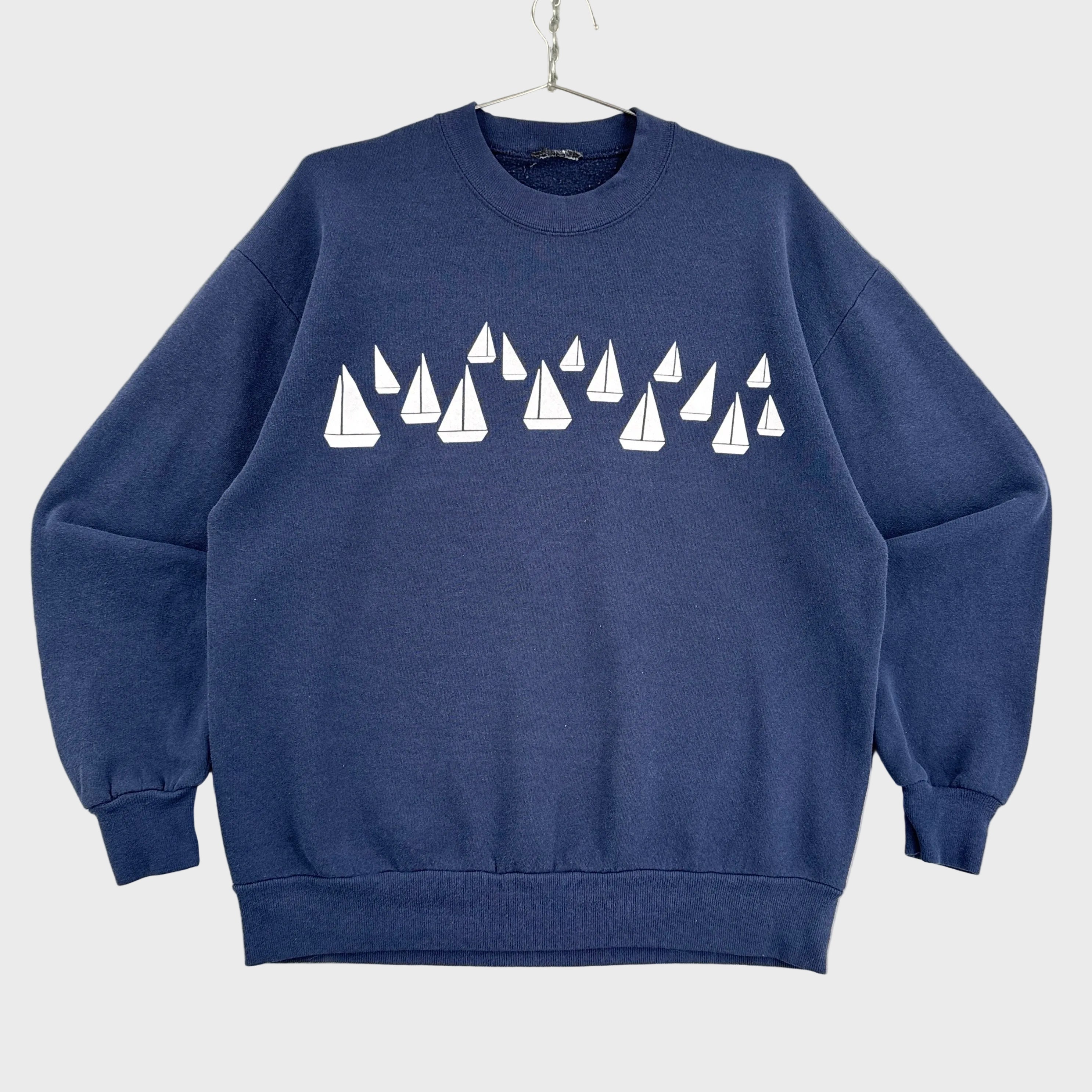 Navy blue sweatshirt with white sailboat pattern on a neutral background