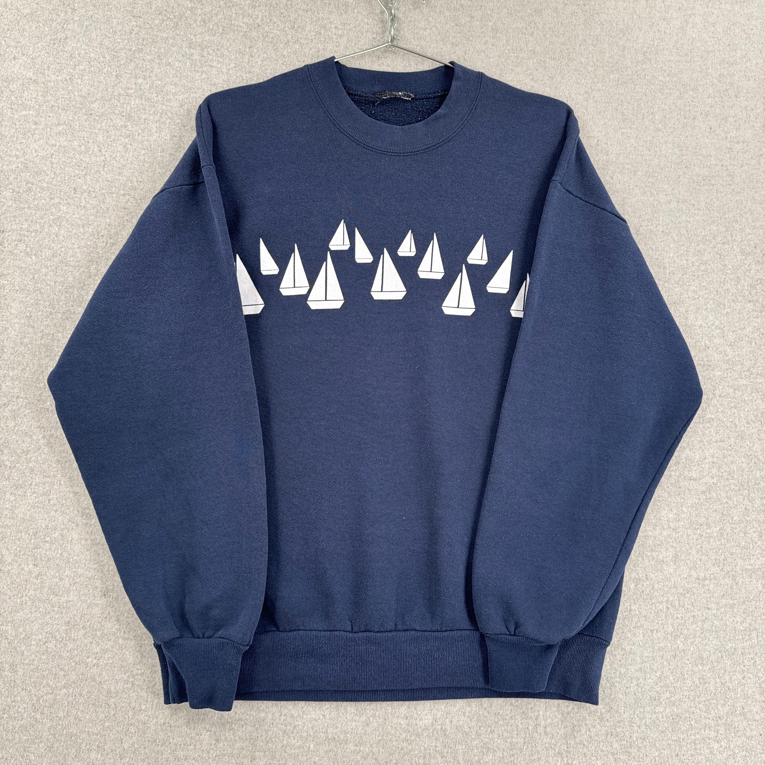 Navy blue sweatshirt with white sailboat pattern on a beige background