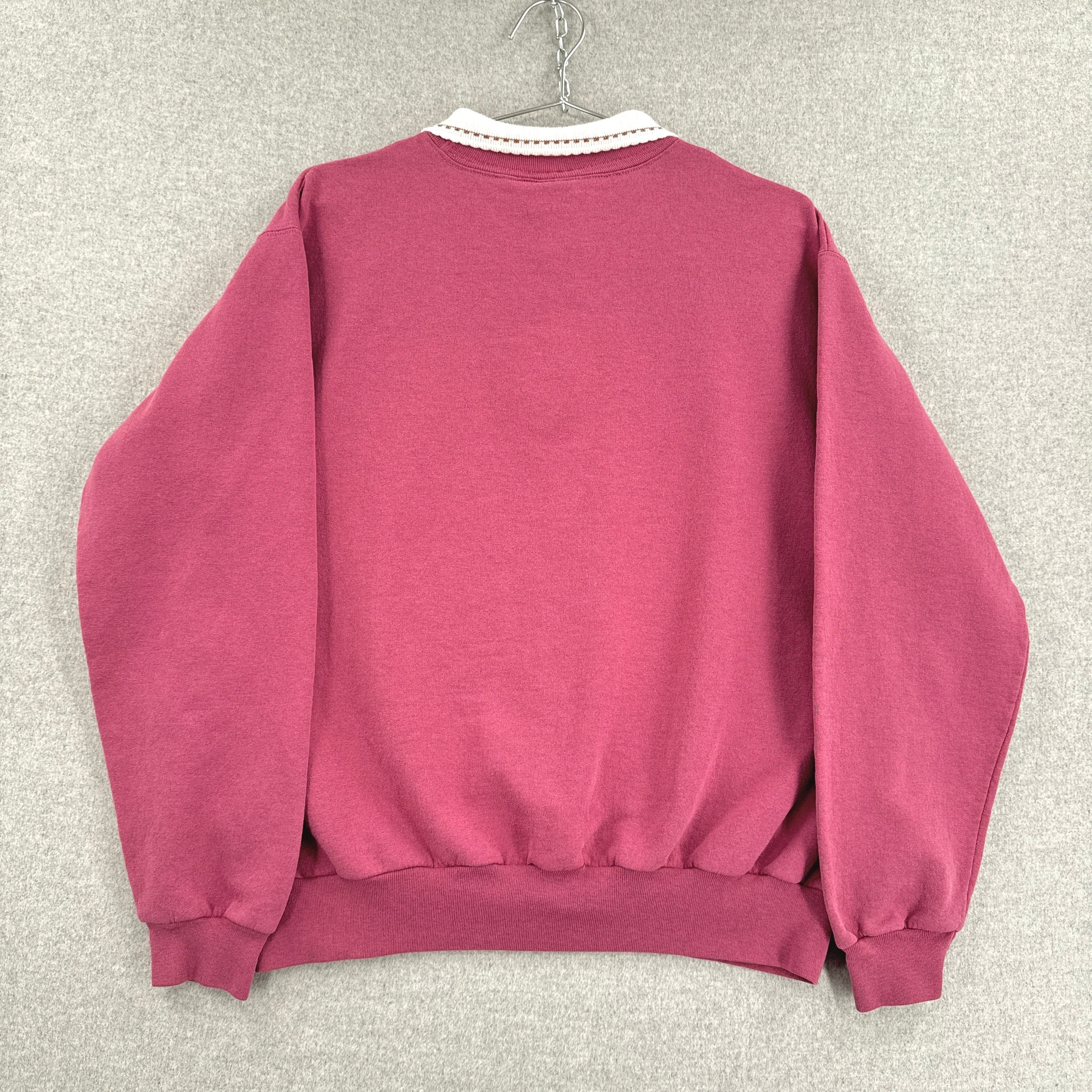 Pink sweatshirt on a hanger against a gray textured wall