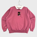 Pink sweatshirt with a small fall leaves graphic on a gray textured background