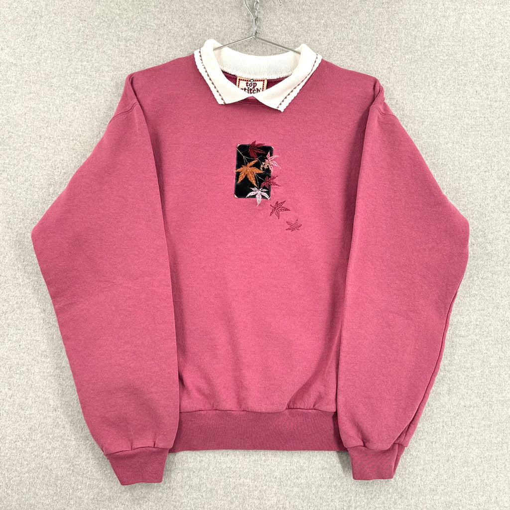 Pink sweatshirt with floral design on a gray background