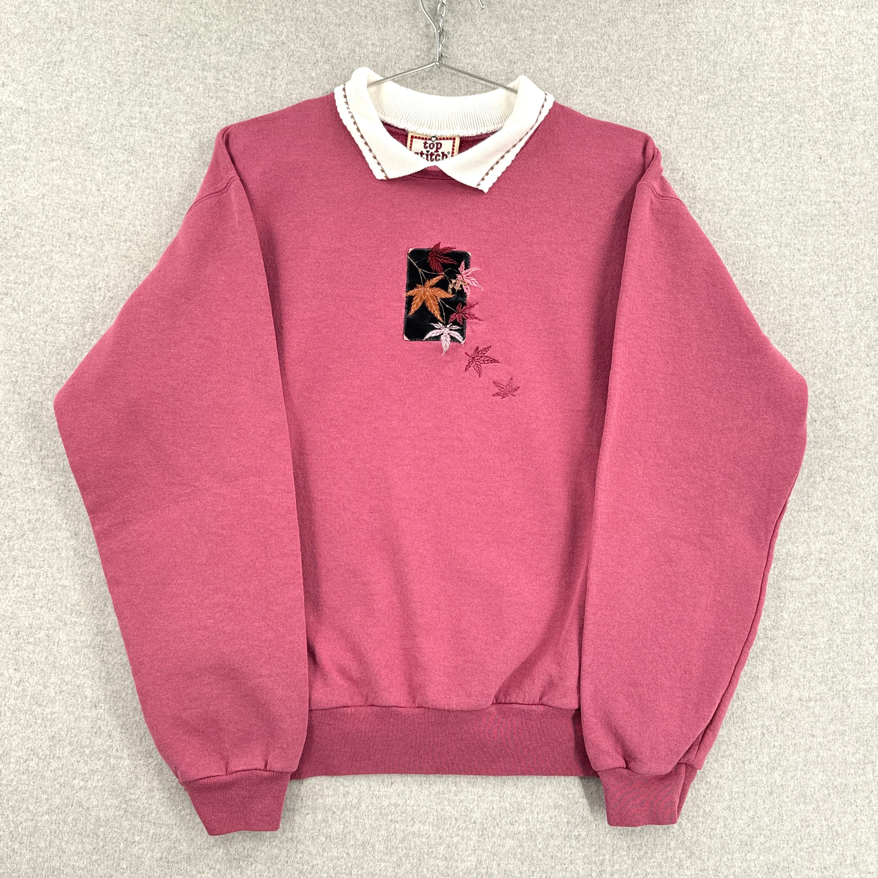 Pink sweatshirt with floral design on a gray background