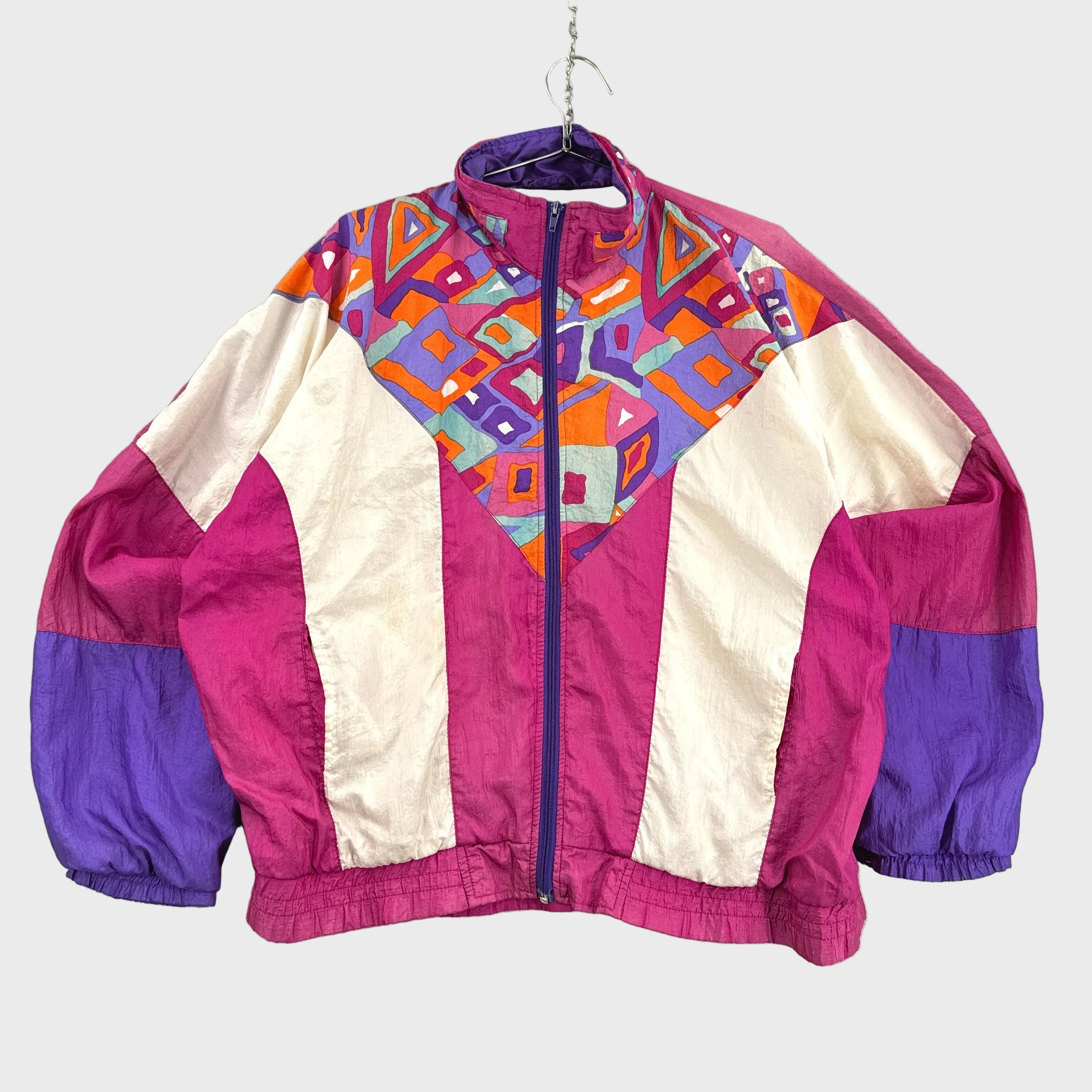 Colorful jacket with geometric pattern on a hanger against a gray background