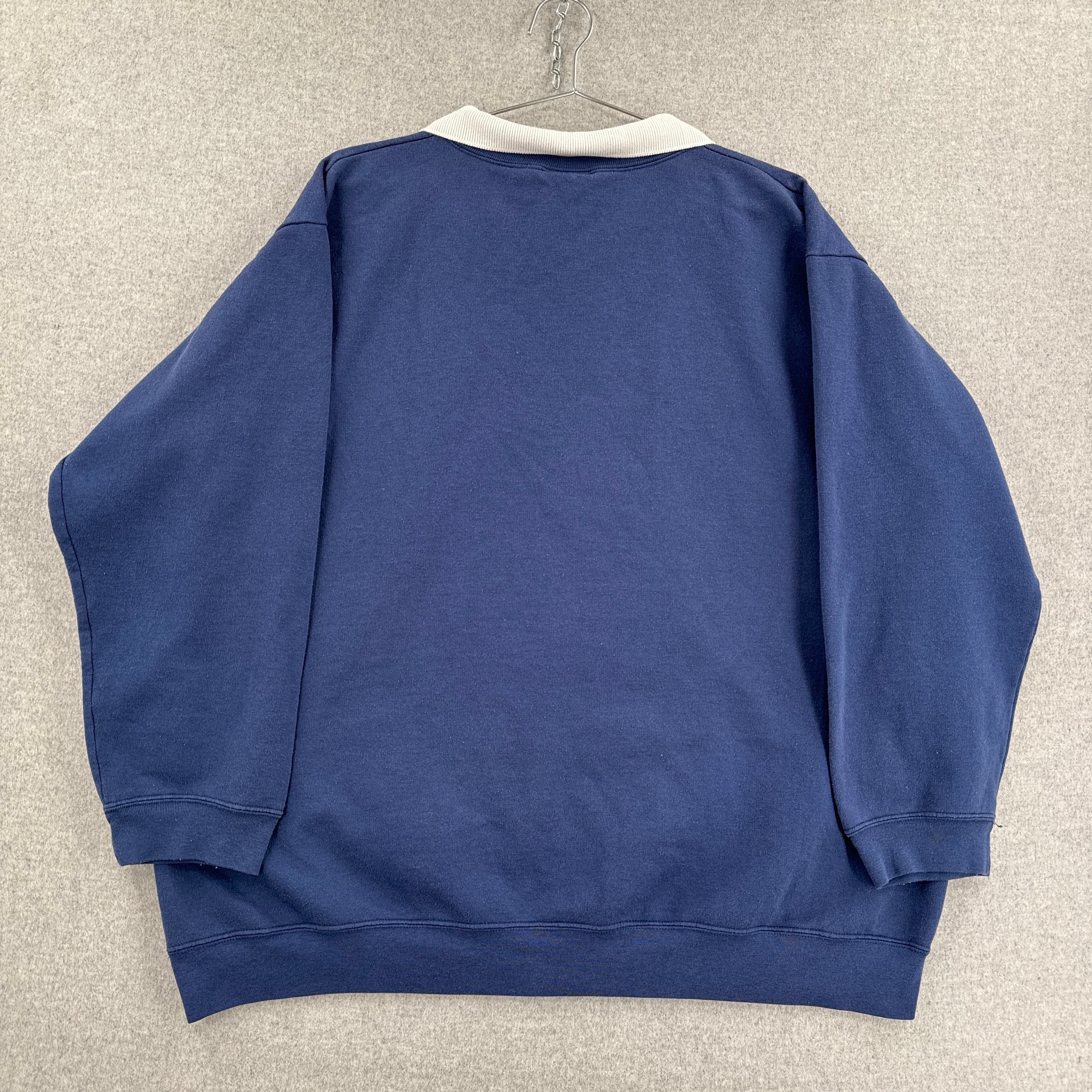 Blue sweatshirt on a hanger against a beige wall