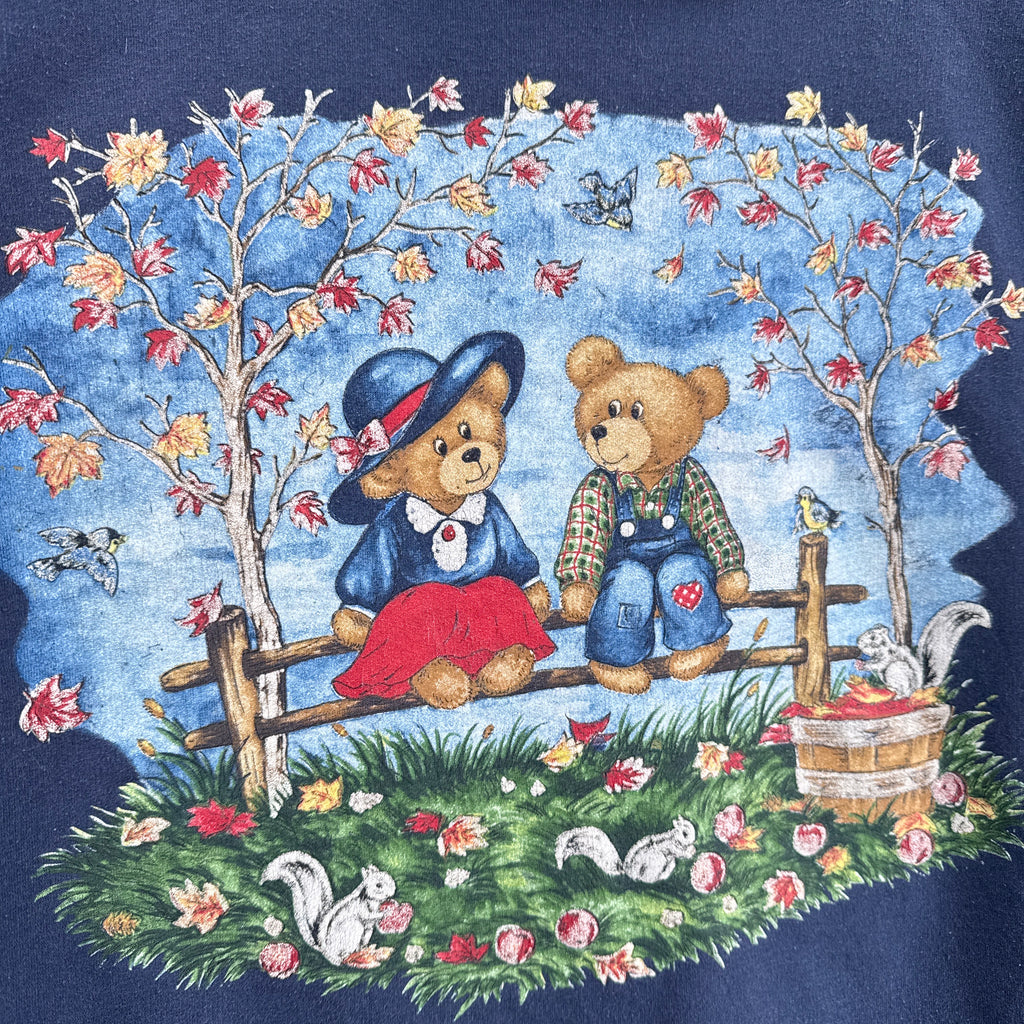 Decorative fabric with teddy bears, fall leaves tree, and floral elements on a blue background with squirrels