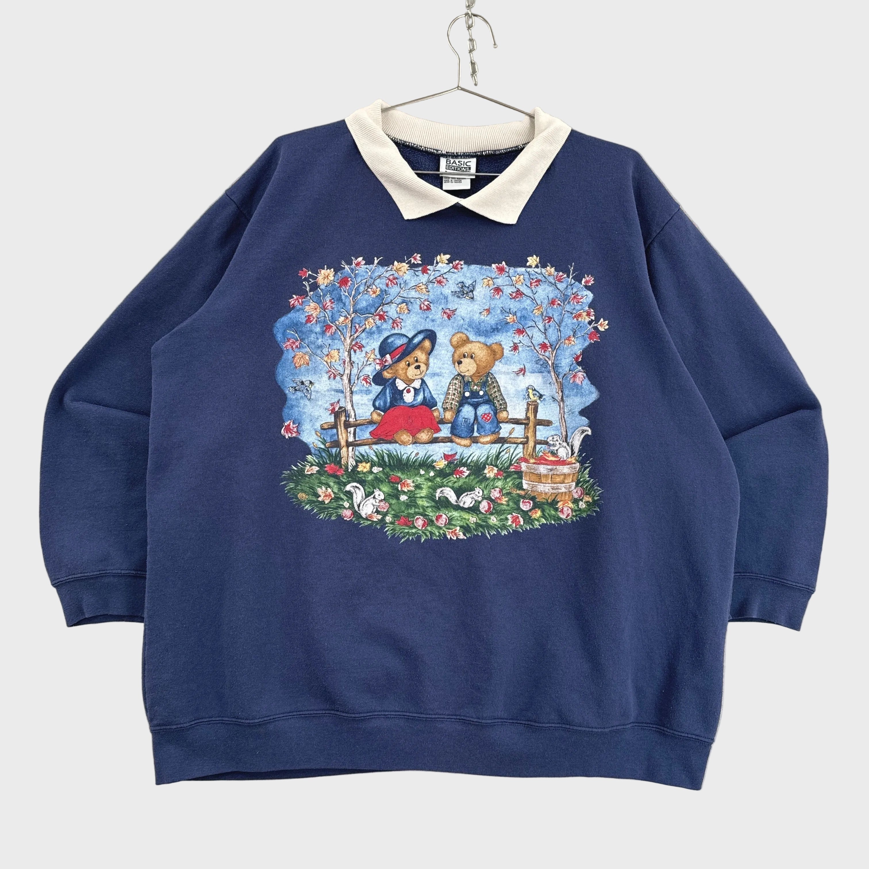 Navy blue sweatshirt with teddy bear design on a beige background
