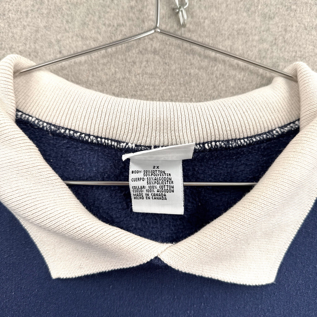 Navy sweater with white collar and brand tag on a hanger. Tag size 2XL made in Canada 50/50 cotton polyester