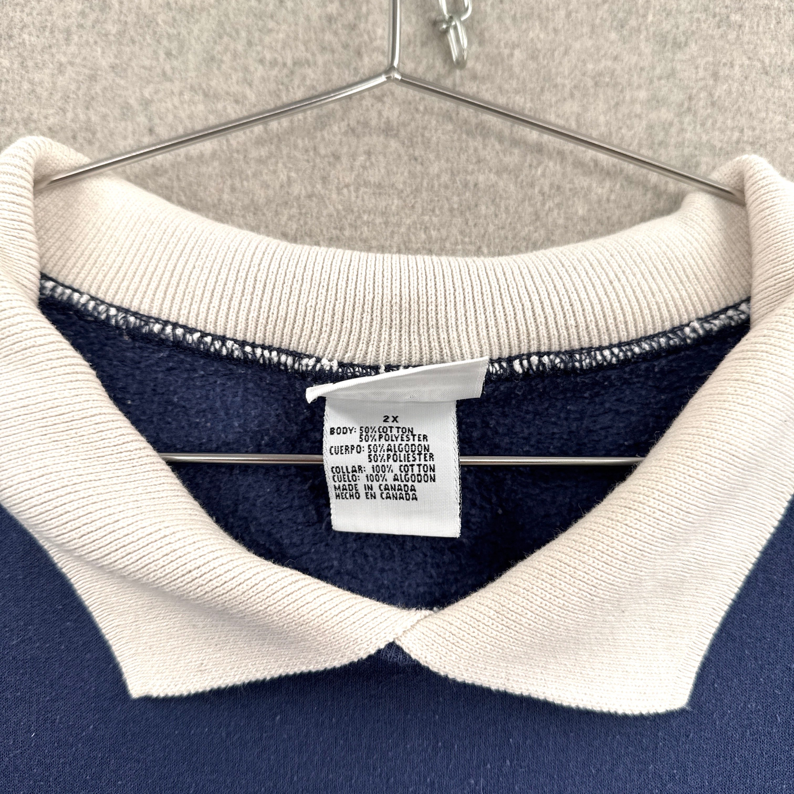 Navy sweater with white collar and brand tag on a hanger. Tag size 2XL made in Canada 50/50 cotton polyester