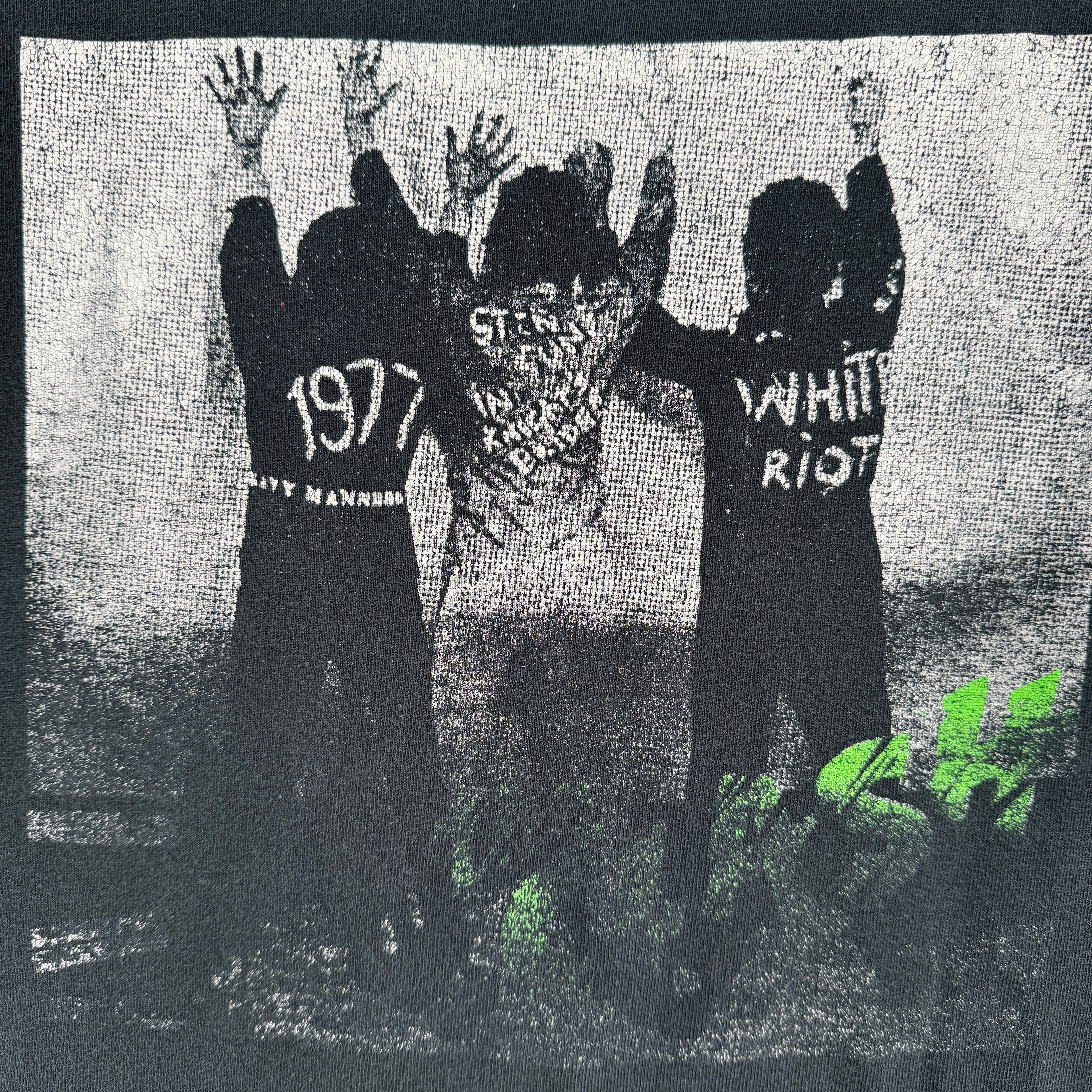 Black t-shirt with graphic design/ The Clash White Riot. Graphic of 3 men with their hands up against a wall.