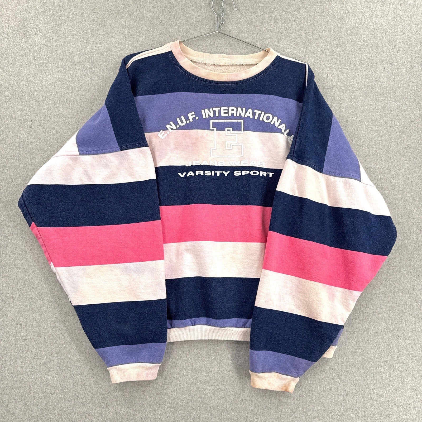 Striped sweater with 'N.U.F. International Varsity Sport' text on a gray background