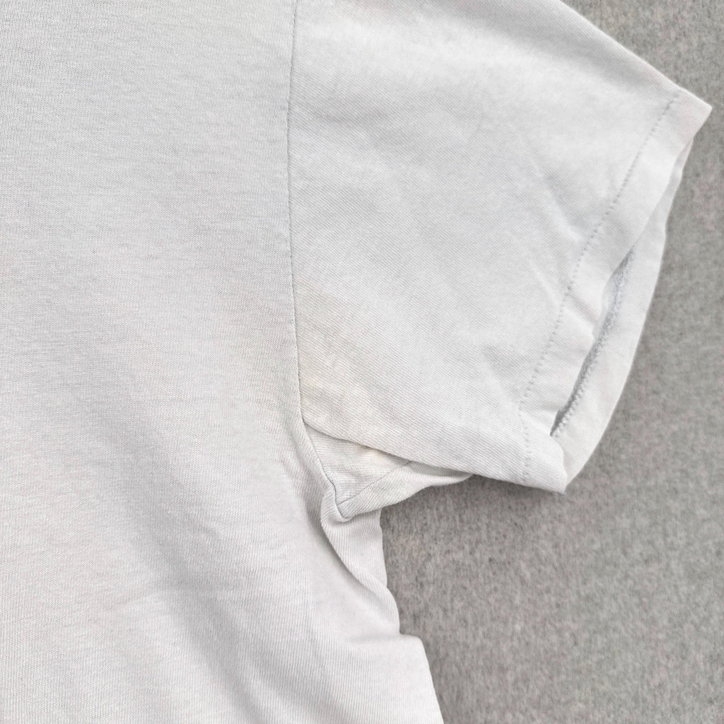 Close-up of a white t-shirt on a gray background, discoloruation around armpit