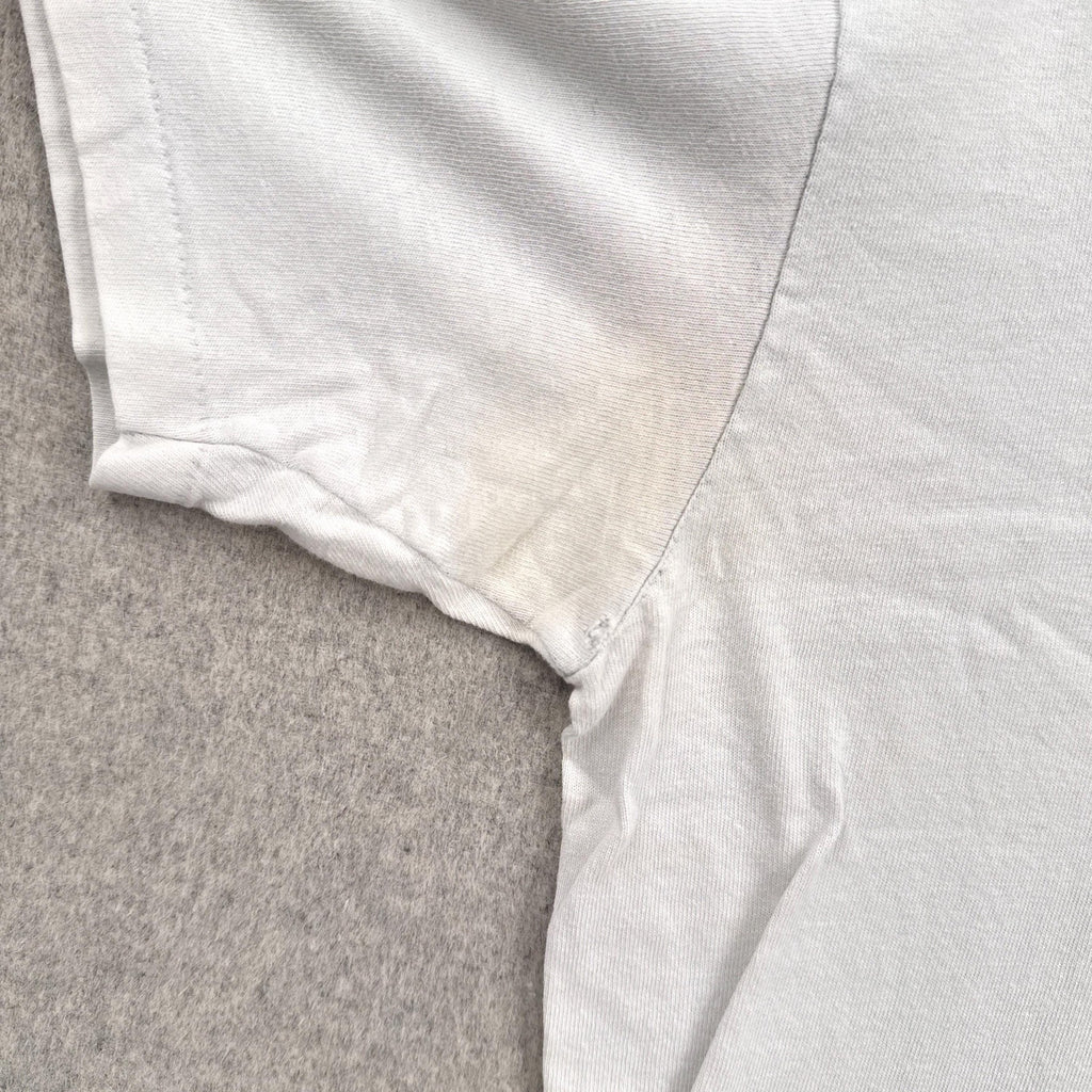 Close-up of a white shirt collar on a textured gray surface. discolouration and hole around armpit