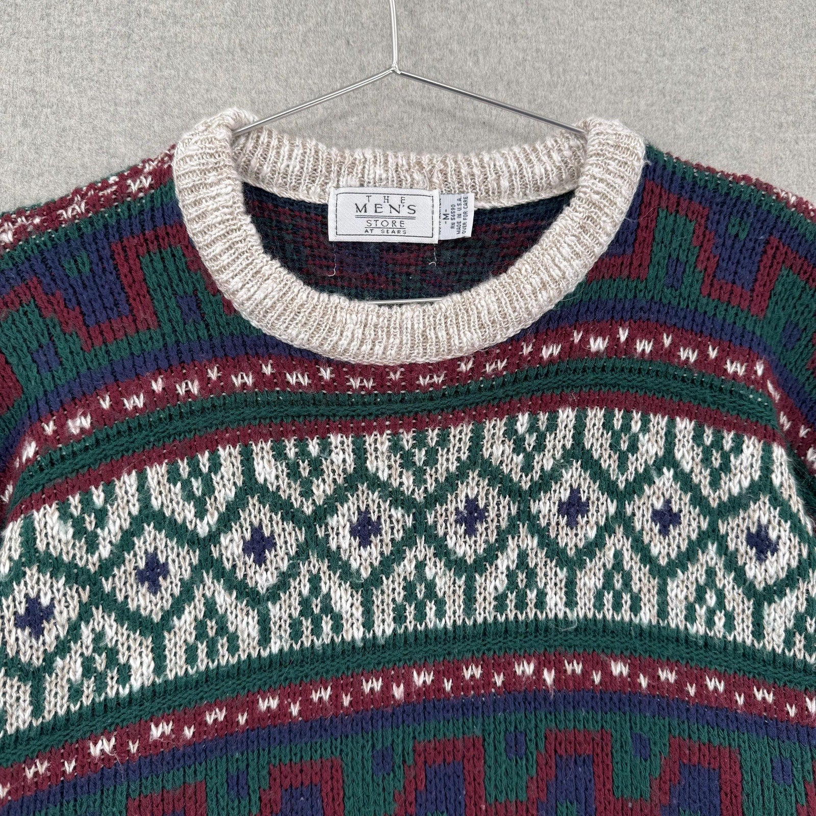 Colorful patterned sweater on a hanger with a visible brand label.