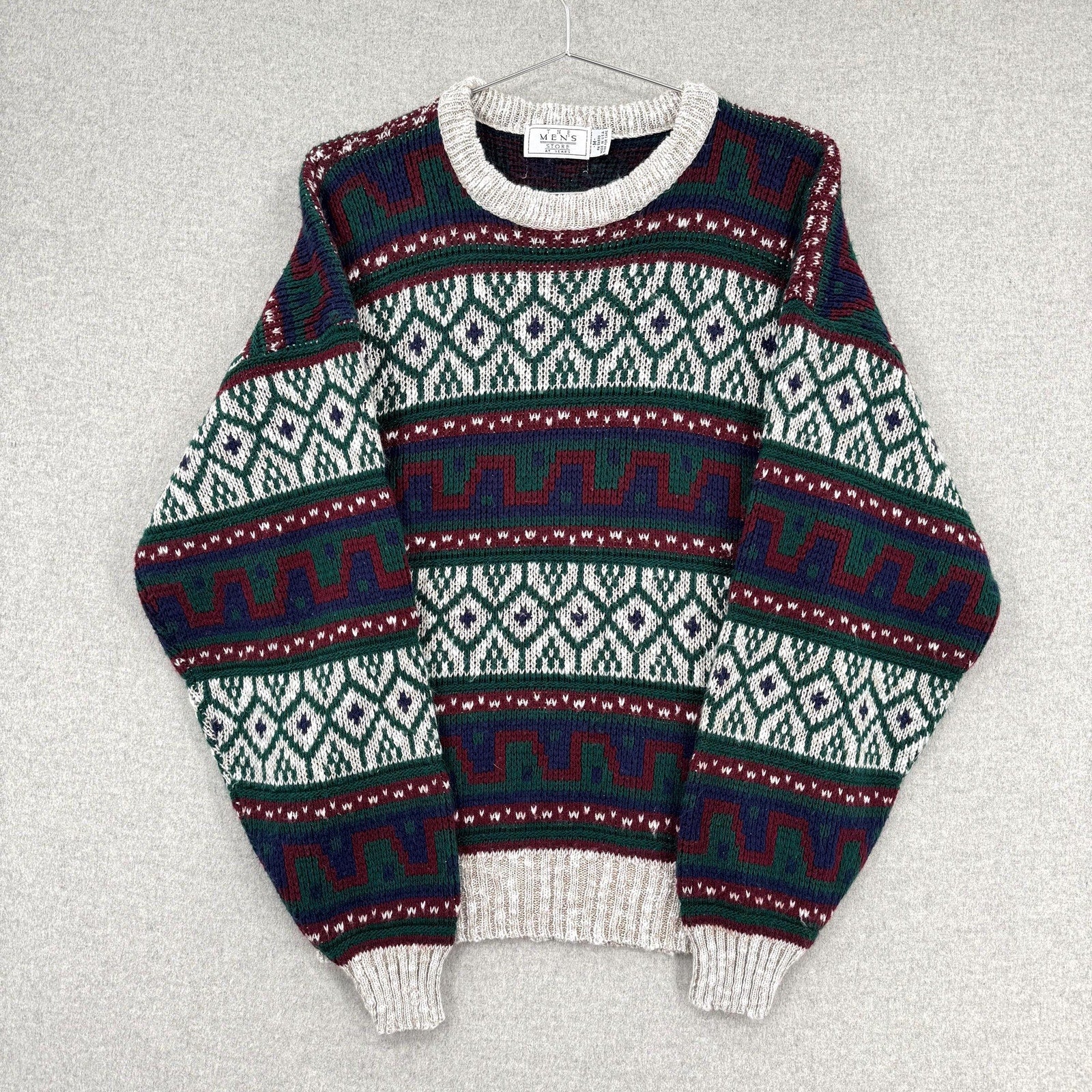 Patterned sweater on a hanger against a gray background