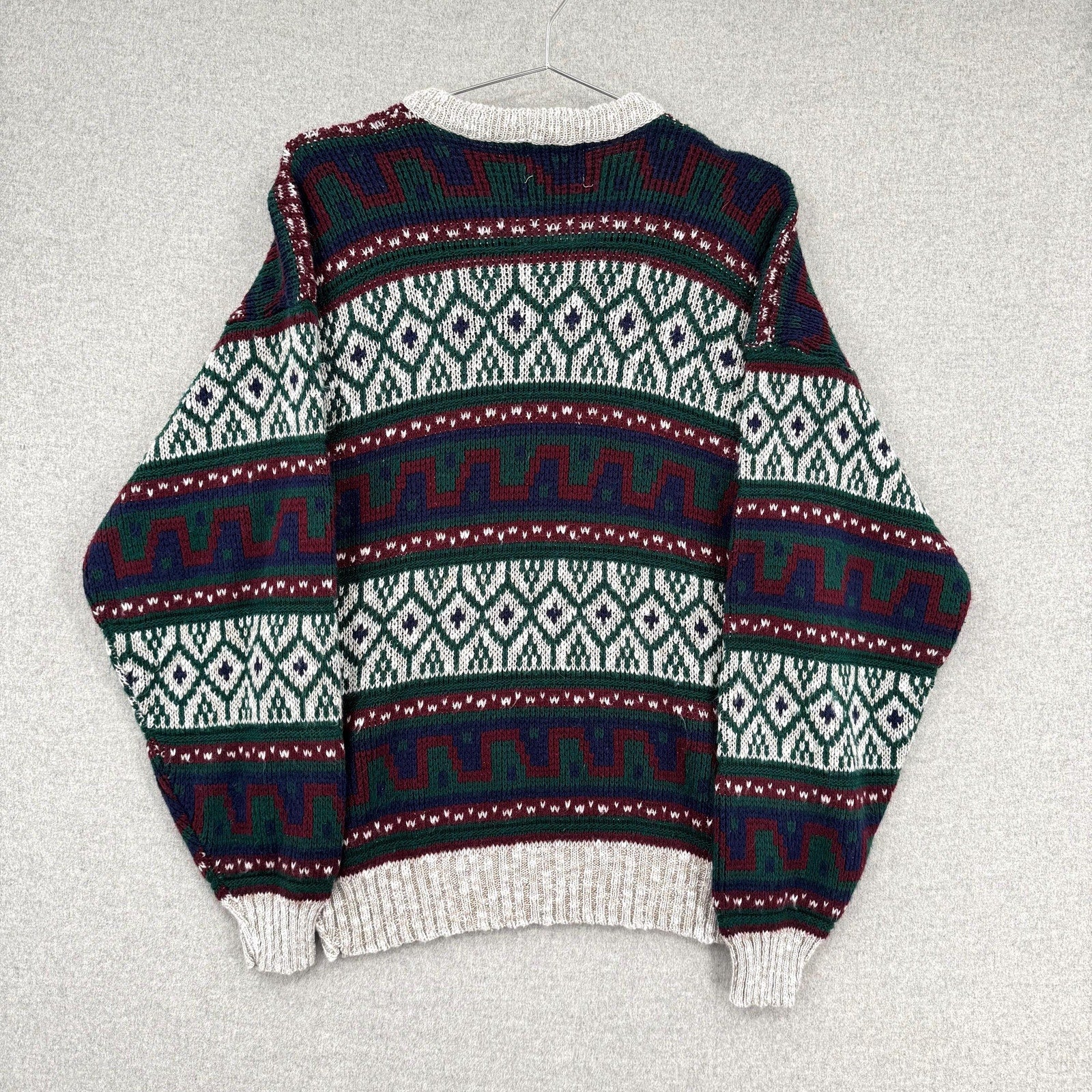 Patterned sweater on a hanger against a light gray background