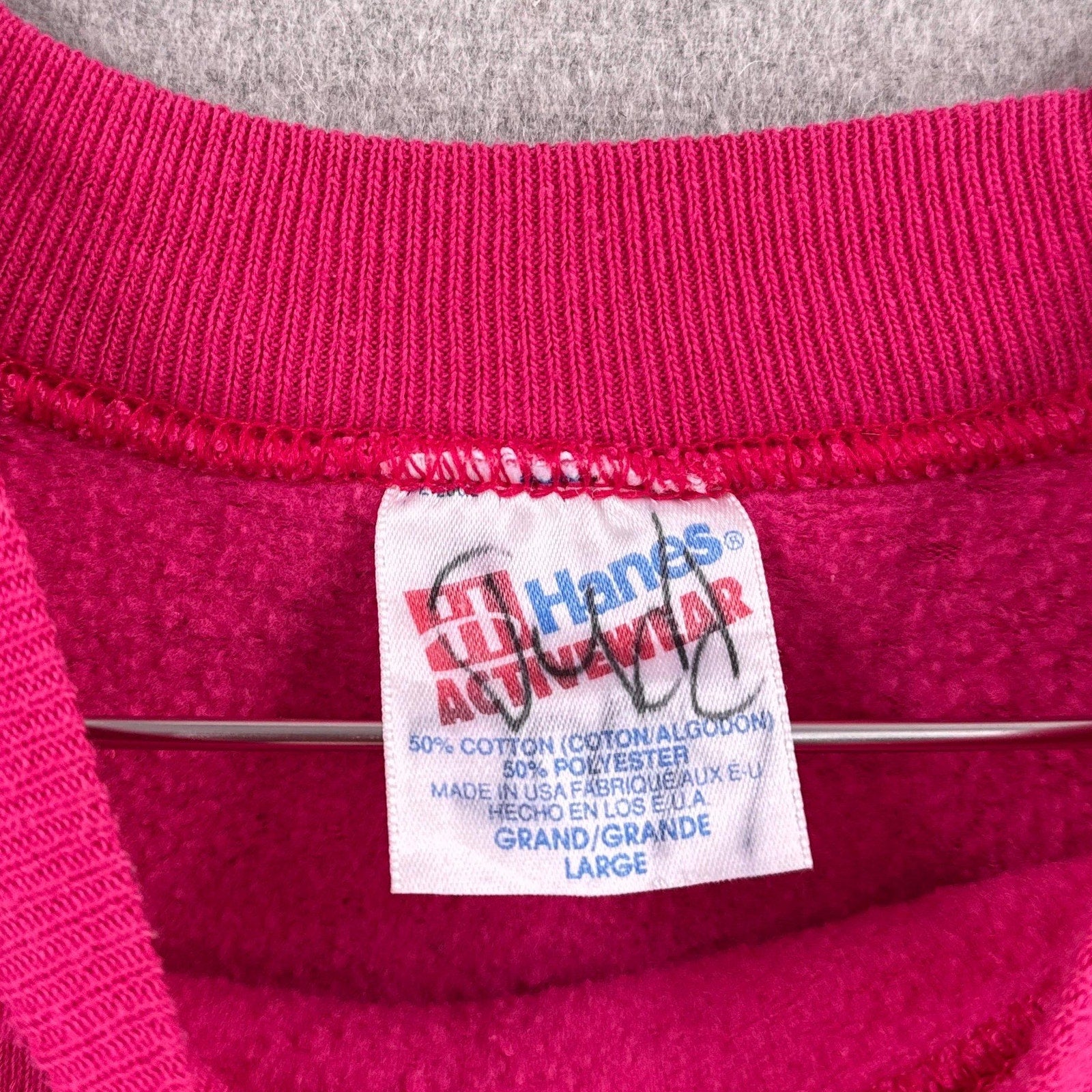 Close-up of a Hanes tag on a pink garment with gray trim. made in USA size Large
