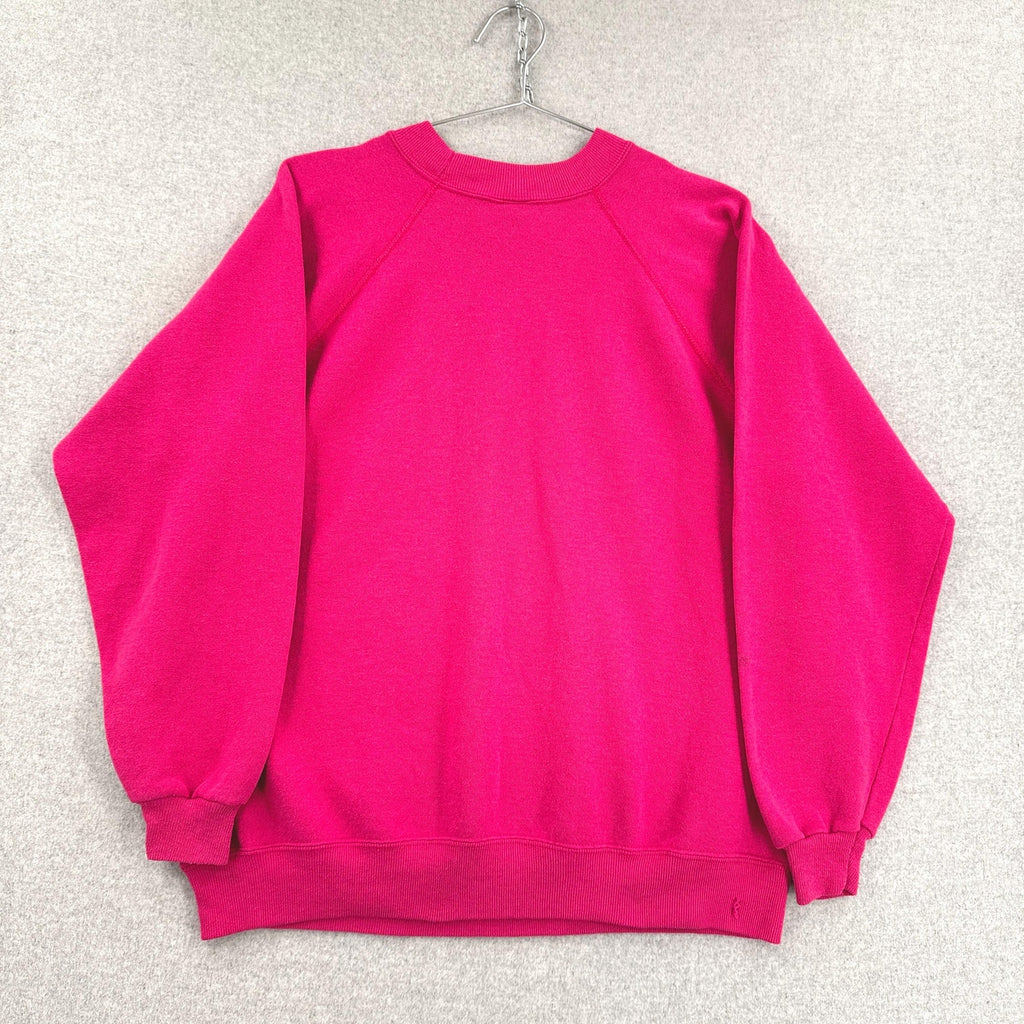 Hot pink sweatshirt on a hanger against a textured white background