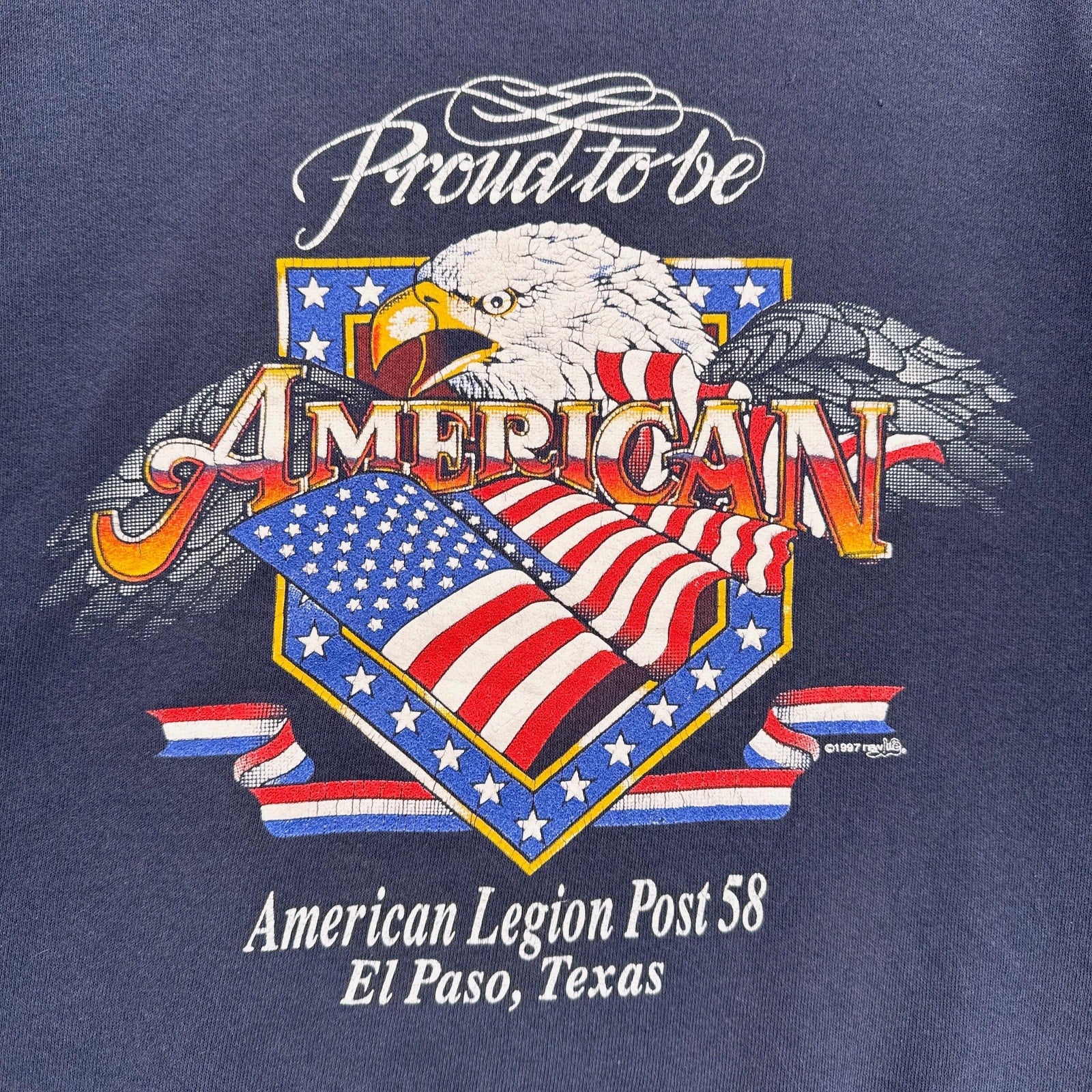 Navy blue t-shirt with an eagle and American flag design, featuring text 'Proud to be American' and 'American Legion Post 58 El Paso, Texas'.