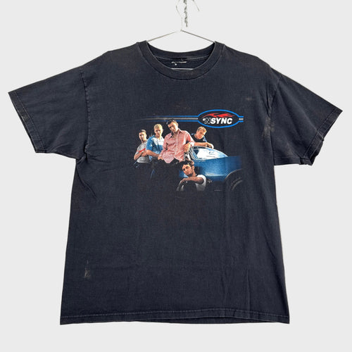 Black t-shirt with graphic design of a boy band NSYNC, hanging on a gray textured surface.
