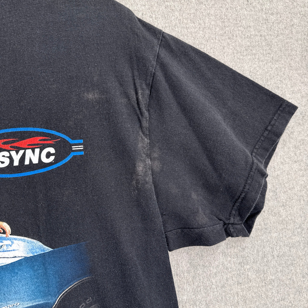 Black shirt with a logo on a gray surface, stain spots near armpit