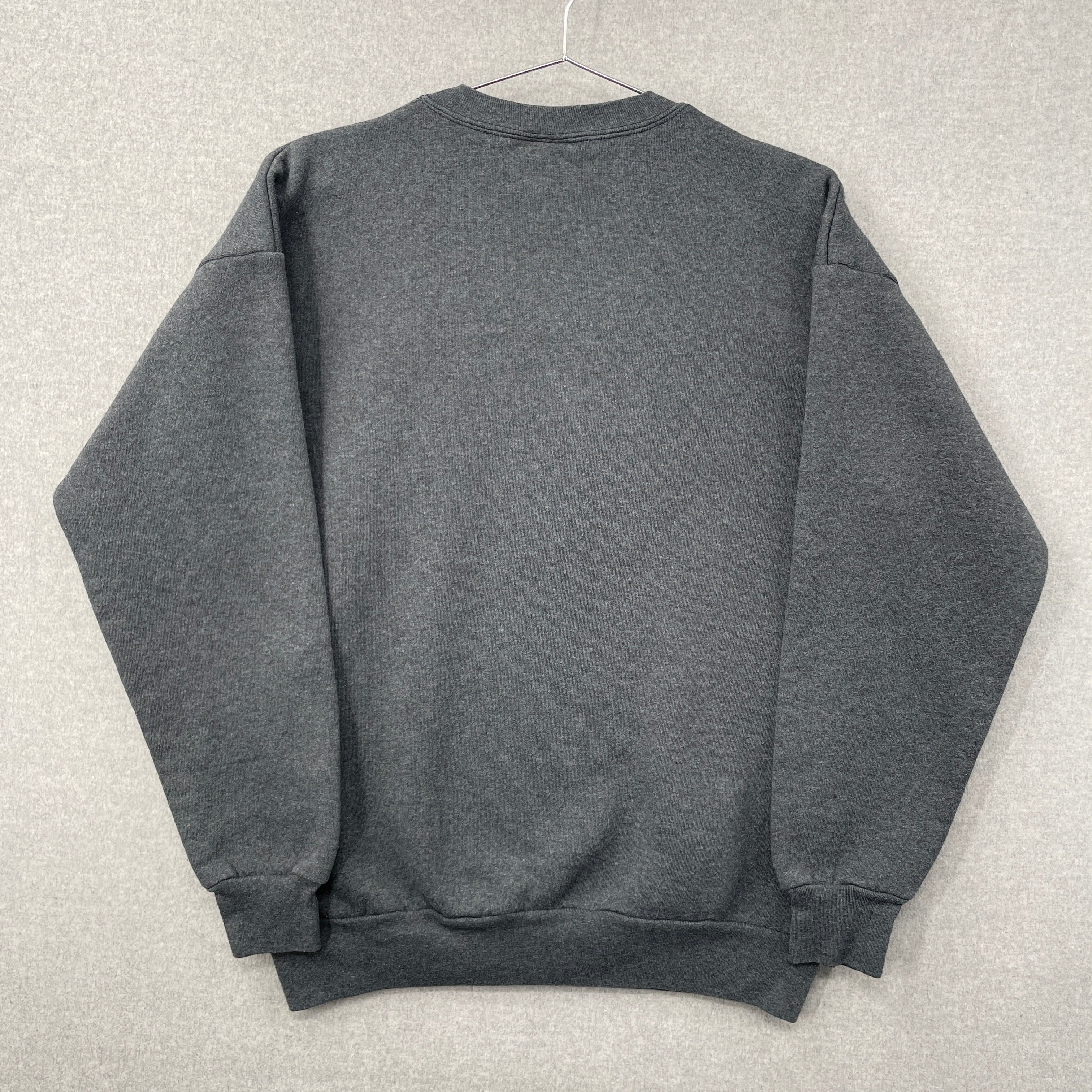 Gray sweatshirt folded on a light gray surface. Blank back of sweatshirt