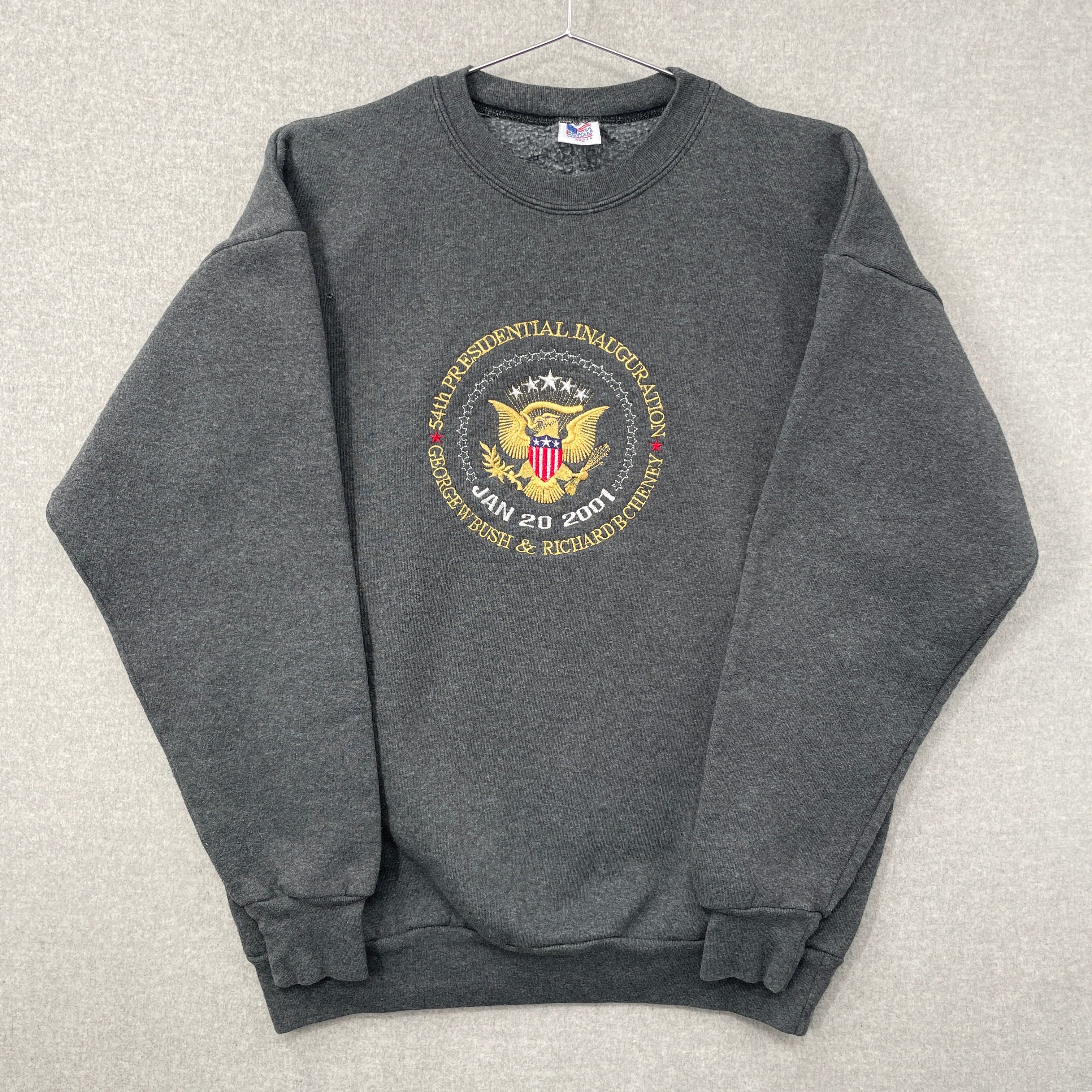 Gray sweatshirt with a logo on a light gray background. sleeves folded over.