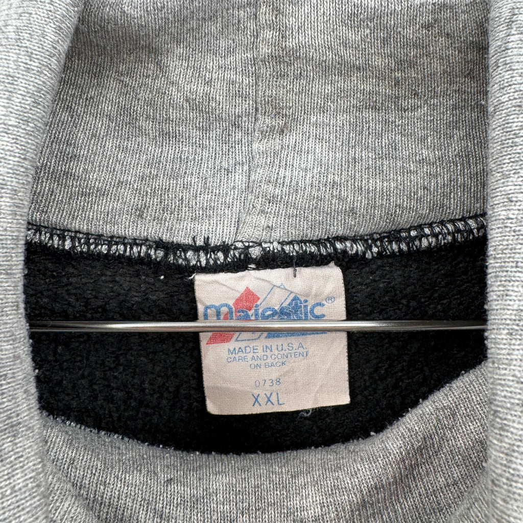 Close-up of a Majestic label on a gray sweatshirt with black trim. Size XXL make in USA