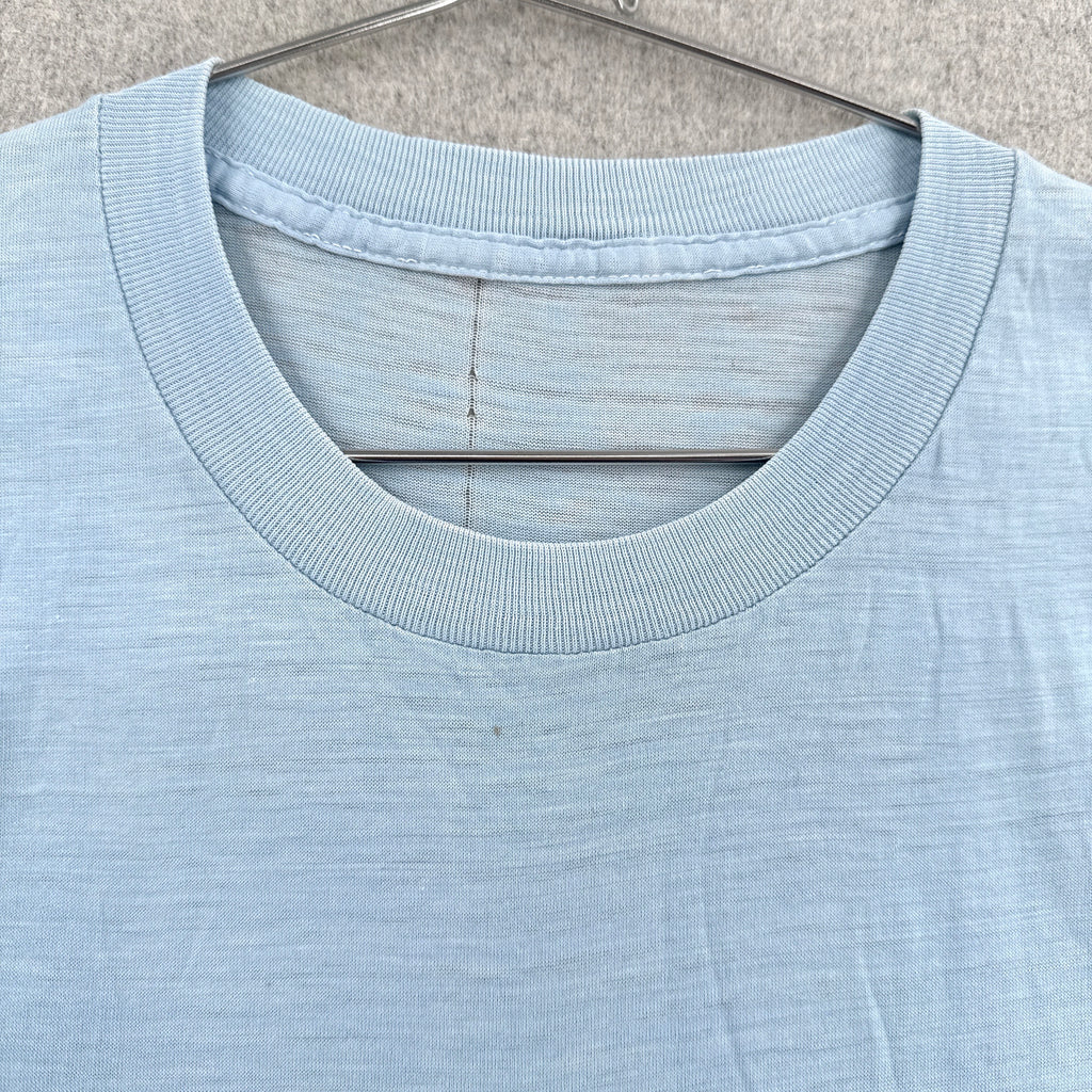 Light blue t-shirt on a hanger against a neutral background. No tag, small stain spot around collar