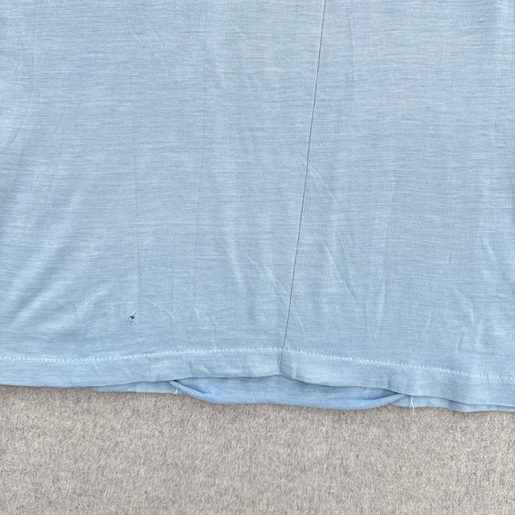 Close-up of a blue fabric with a visible seam detached on a gray surface.
