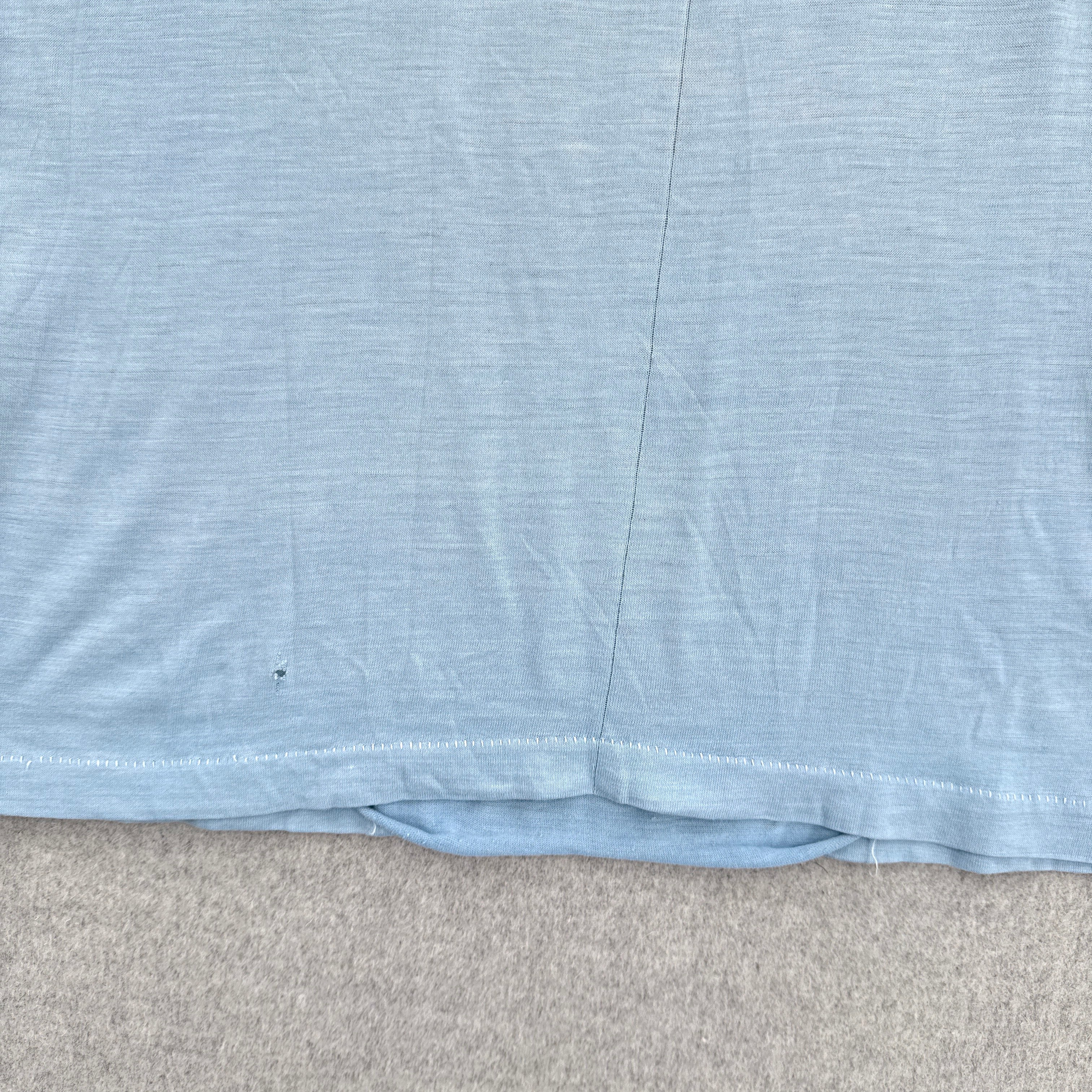 Close-up of a blue fabric with a visible seam detached on a gray surface.