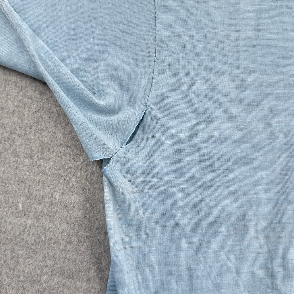 Close-up of light blue fabric with a visible rip in armpit