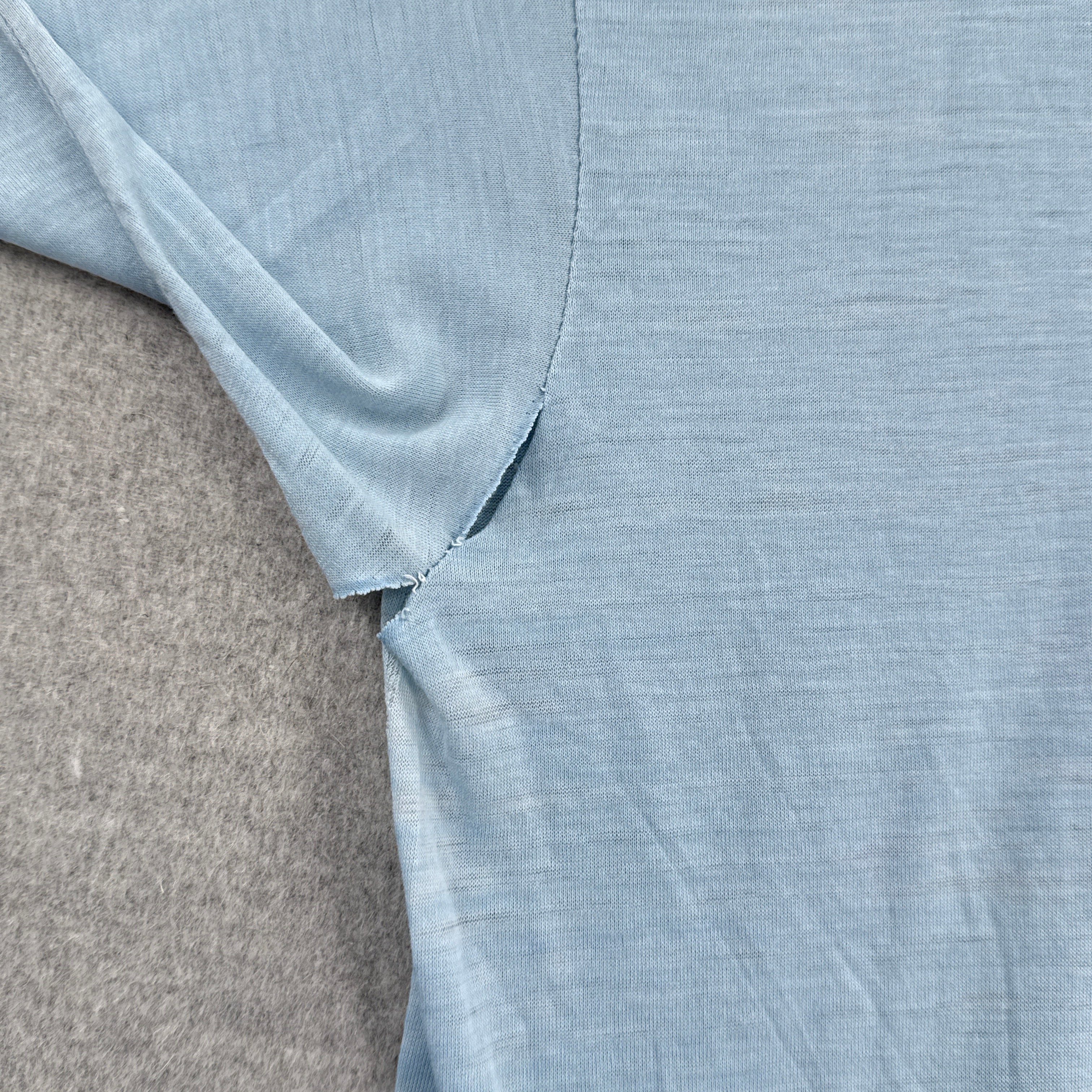 Close-up of light blue fabric with a visible rip in armpit