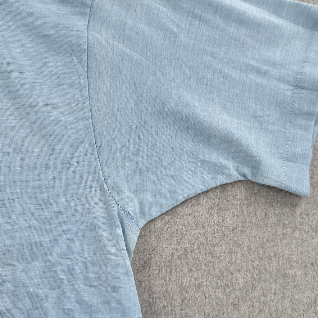 Light blue sleeveless top on a gray surface. small hole in armpit