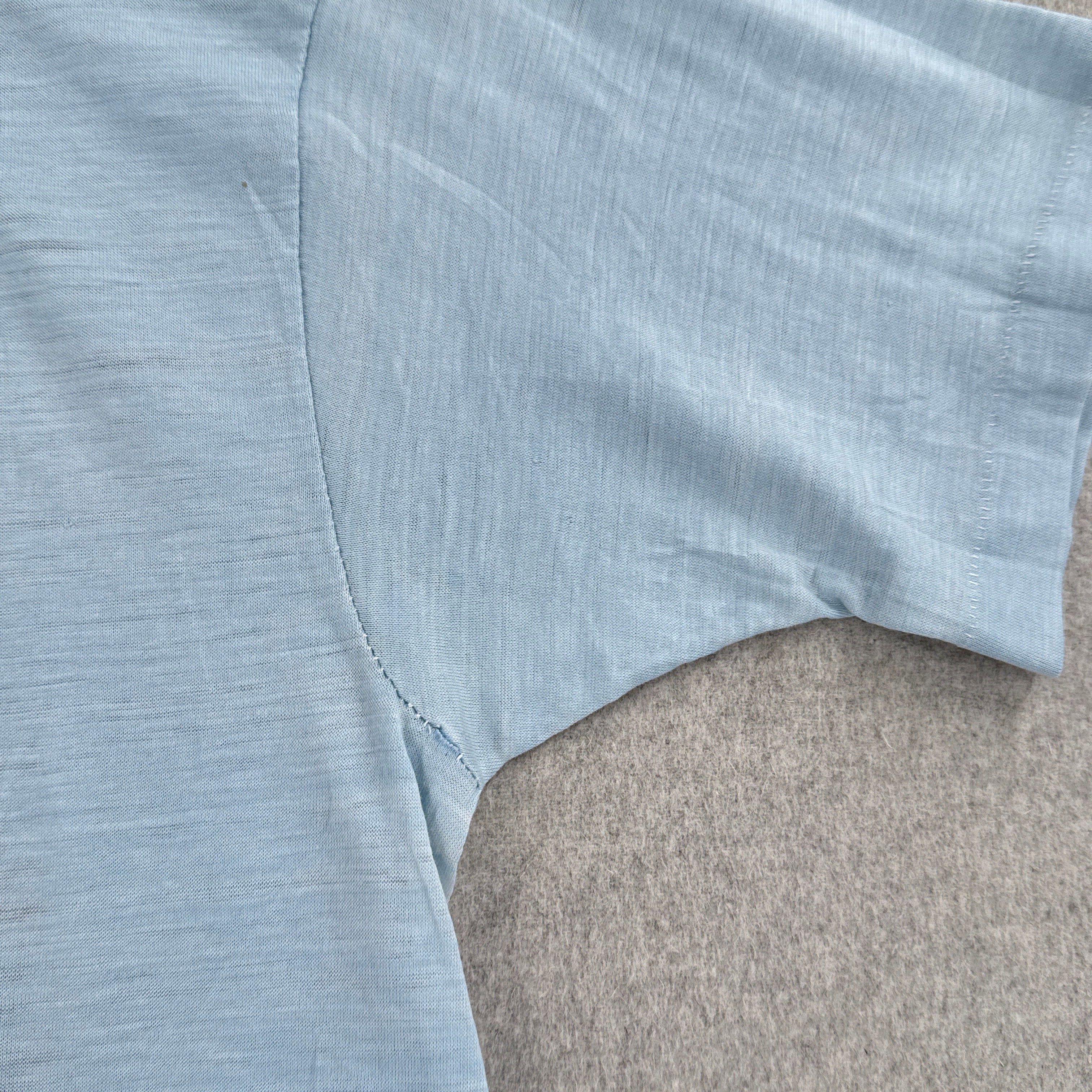 Light blue sleeveless top on a gray surface. small hole in armpit